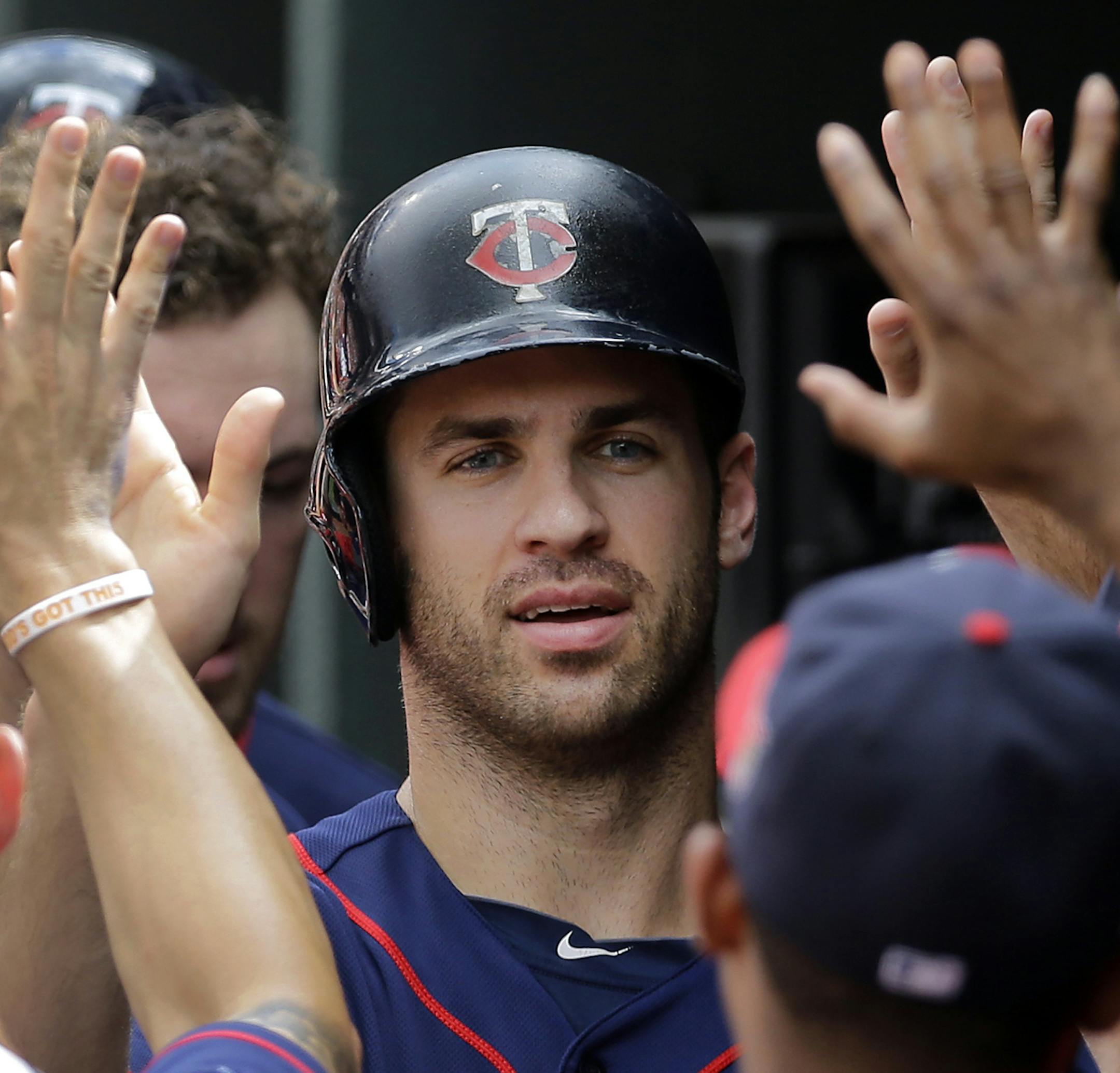 Minnesota Twins' Joe Mauer high-fives teammates in the dugout after scoring on a Kennys Vargas sacrifice fly ball in the sixth inning of a baseball game against the Baltimore Orioles, Monday, Sept. 1, 2014, in Baltimore. (AP Photo/Patrick Semansky)