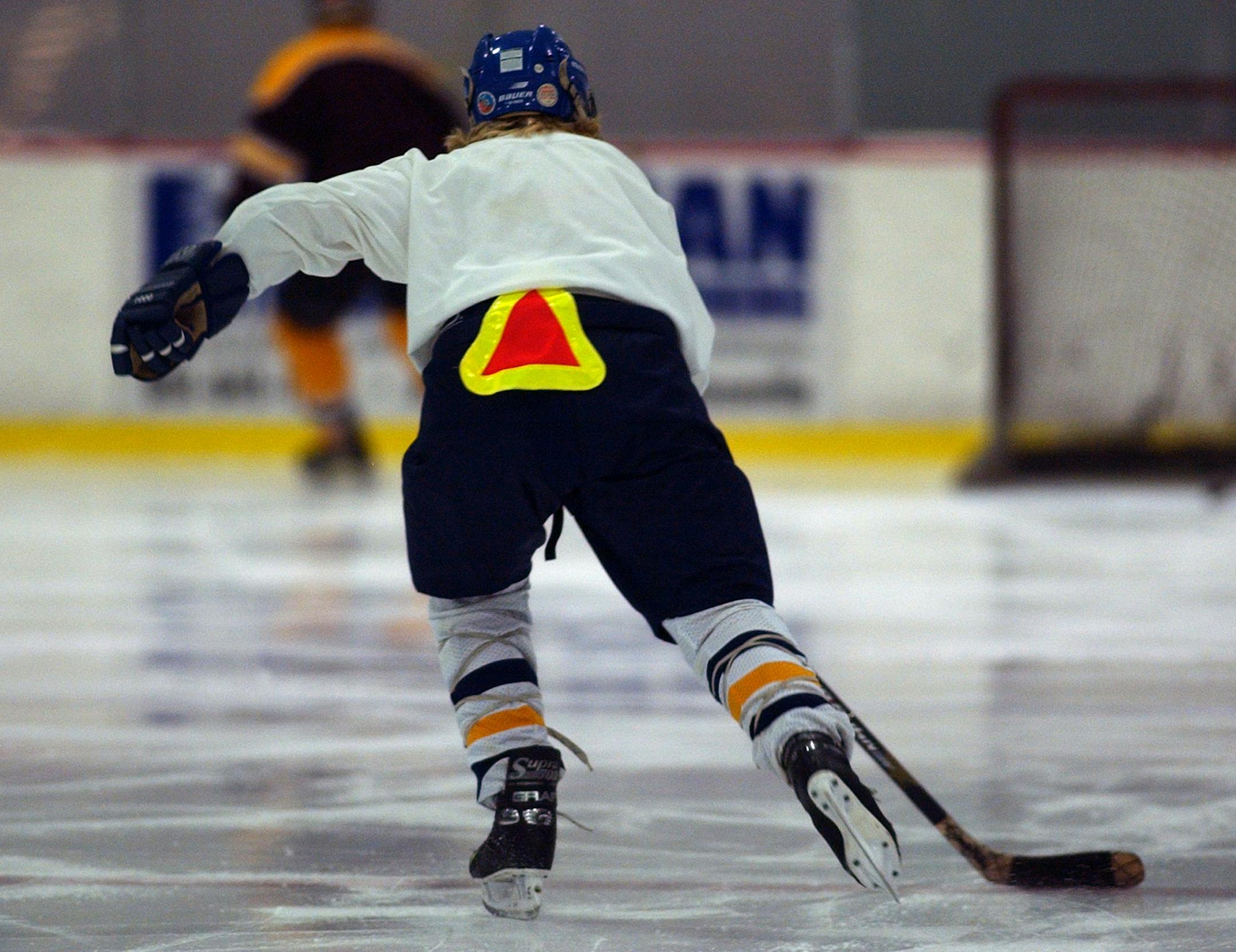 Roseville, Mn., Tues., Dec. 9, 2003--Recovering from back surgery, Robin Marvin wears a slow-moving vehicle sign on her pants.
GENERAL INFORMATION: Jane Ring and Sue Jarvi, mother and daughter, play hockey together with other women at Roseville Arena.