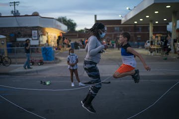 Marcia Howard jumped double dutch jump rope with Silas Yechout, 10, during a community dinner at the George Floyd memorial at 38th and Chicago in Minn