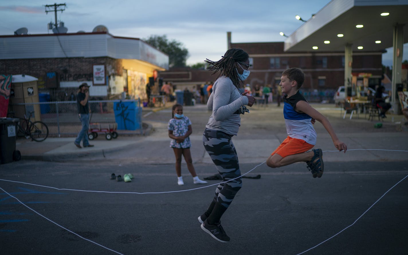 Marcia Howard jumped double dutch jump rope with Silas Yechout, 10, during a community dinner at the George Floyd memorial at 38th and Chicago in Minneapolis, Minn., on Monday, August 31, 2020. Both live in the neighborhood. Marcia has become one of the leaders keeping the memorial organized and safe. ] RENEE JONES SCHNEIDER renee.jones@startribune.com Marcia Howard lives around the corner from the spot George Floyd was killed in front of Cup Foods at 38th and Chicago. She has dedicated her life