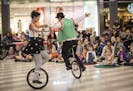 Rhiannon Davis and Earl McKenzie of Lime Tree Circus hold hands while riding unicycles during a Toddler Tuesdays event at the Mall of America Tuesday,