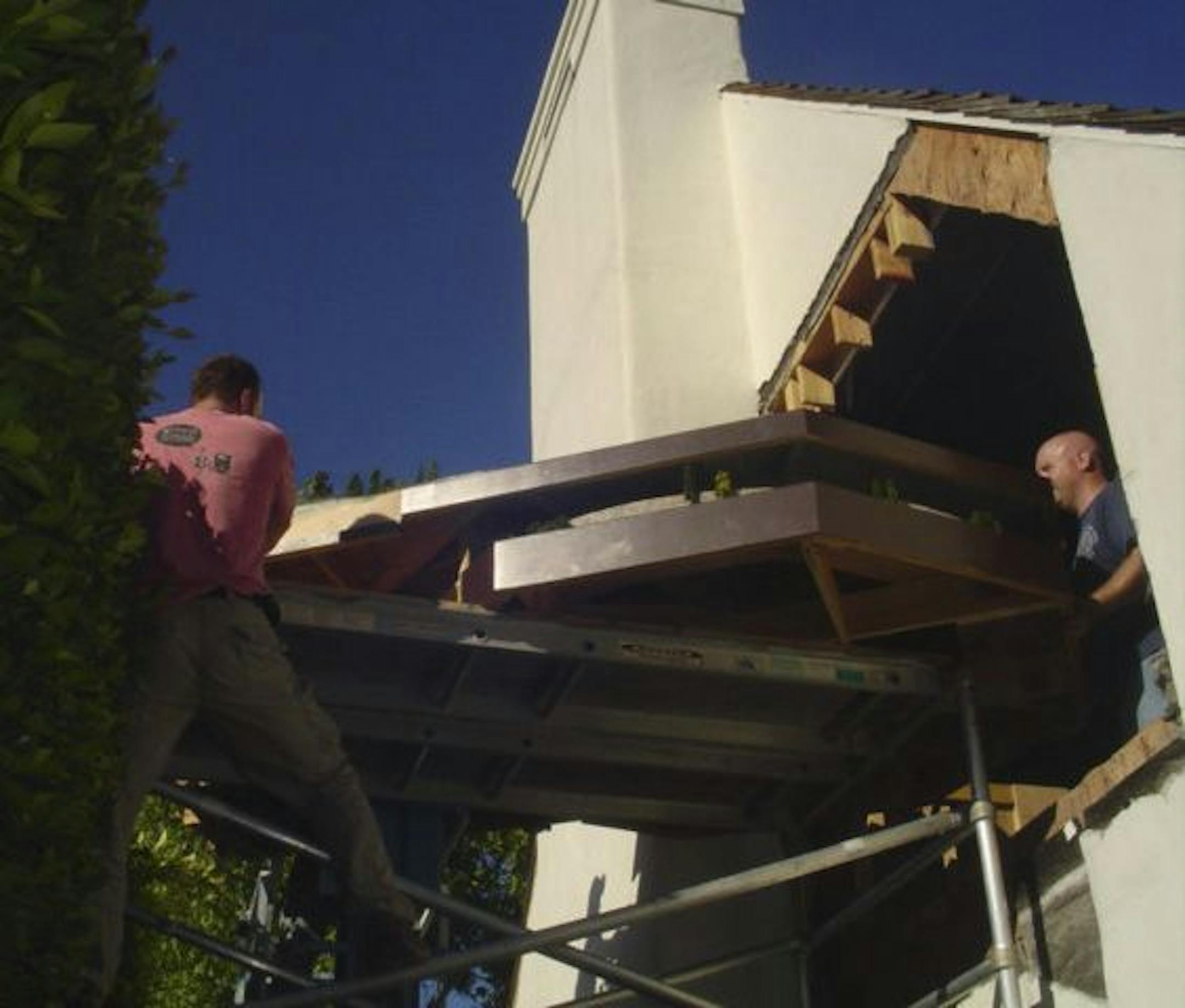 Provided by Chad Kono Easy does it: Brothers Matt (left) and Andy Winiecki removed a piece of the layout from the Santa Barbara, Calif., home of Michael Corrigan. They cut a 10-foot-square hole in the house to get it out.