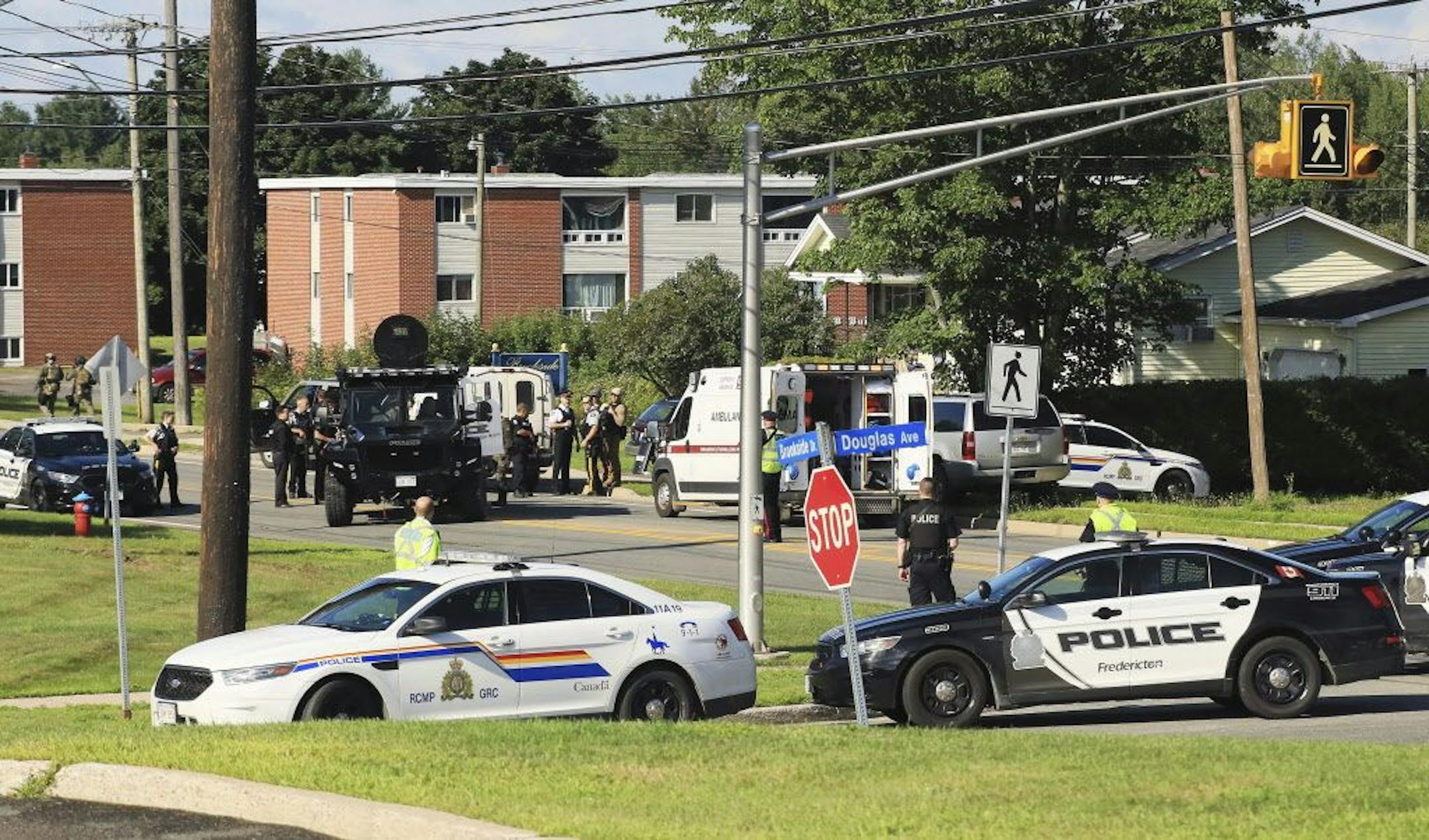 Police and RCMP officers survey the area of a shooting in Fredericton, New Brunswick, Canada on Friday, Aug. 10, 2018. Fredericton police say two officers were among four people who died in a shooting Friday in a residential area on the city's north side. One person was in custody, they said, and there was no further threat to the public.