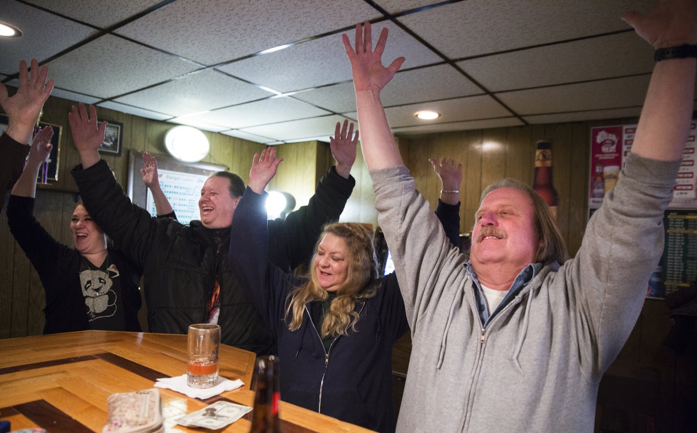 FILE -- Bangor residents hold up their arms to mark the end of happy hour at Bangor Lanes as the 6 p.m. village siren wails in Bangor, Wis. on Tuesday, January 13, 2015. From right is Steve Hanson, Terry Hanson, Rich Atkinson and Erin Lusk.