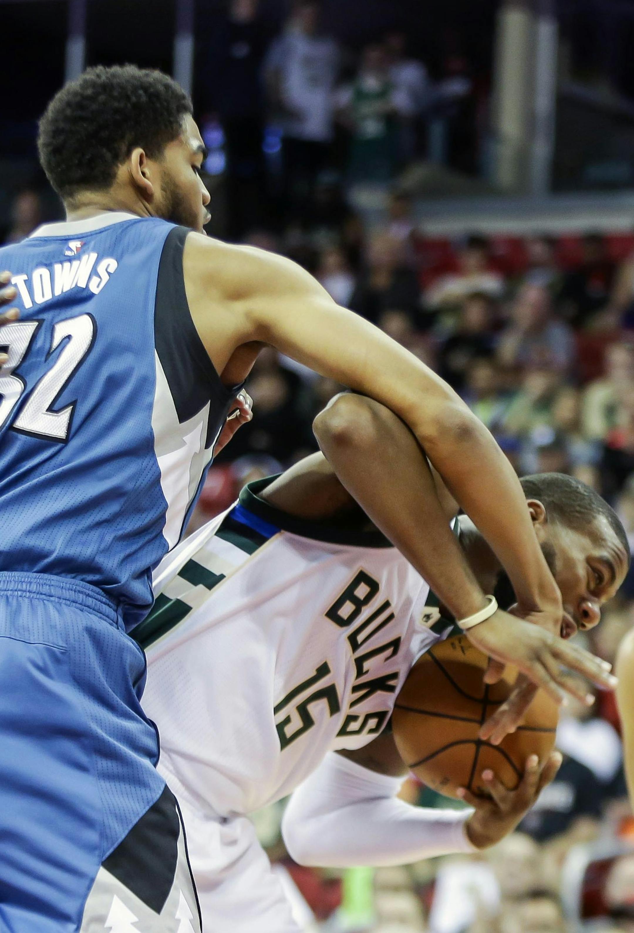 Minnesota Timberwolves' Karl-Anthony Towns (32) reaches in on Milwaukee Bucks' Greg Moore during the first half of an NBA preseason basketball game Tuesday, Oct. 20, 2015, in Madison, Wis. (AP Photo/Andy Manis)