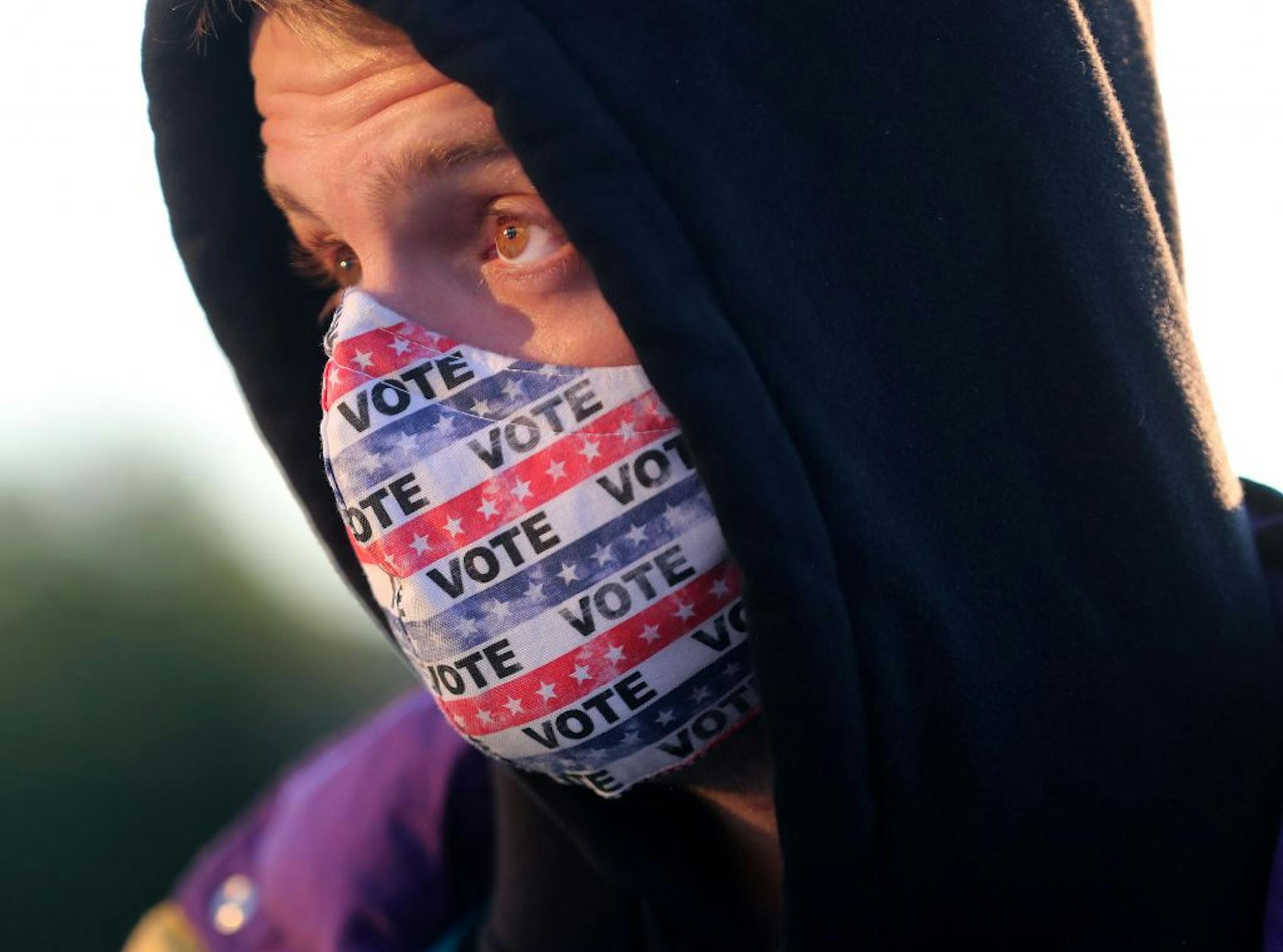 Jack O'Rourke of Minneapolis, whose mother made him a custom mask urging people to vote, joined other voters during early voting at Minneapolis Elections and Voter Services Friday in Minneapolis. O'Rourke said he is looking "at the state of the country," in the pandemic and believes the U.S. is far worse off than other developed nations and that is what he said he will base his vote on.
