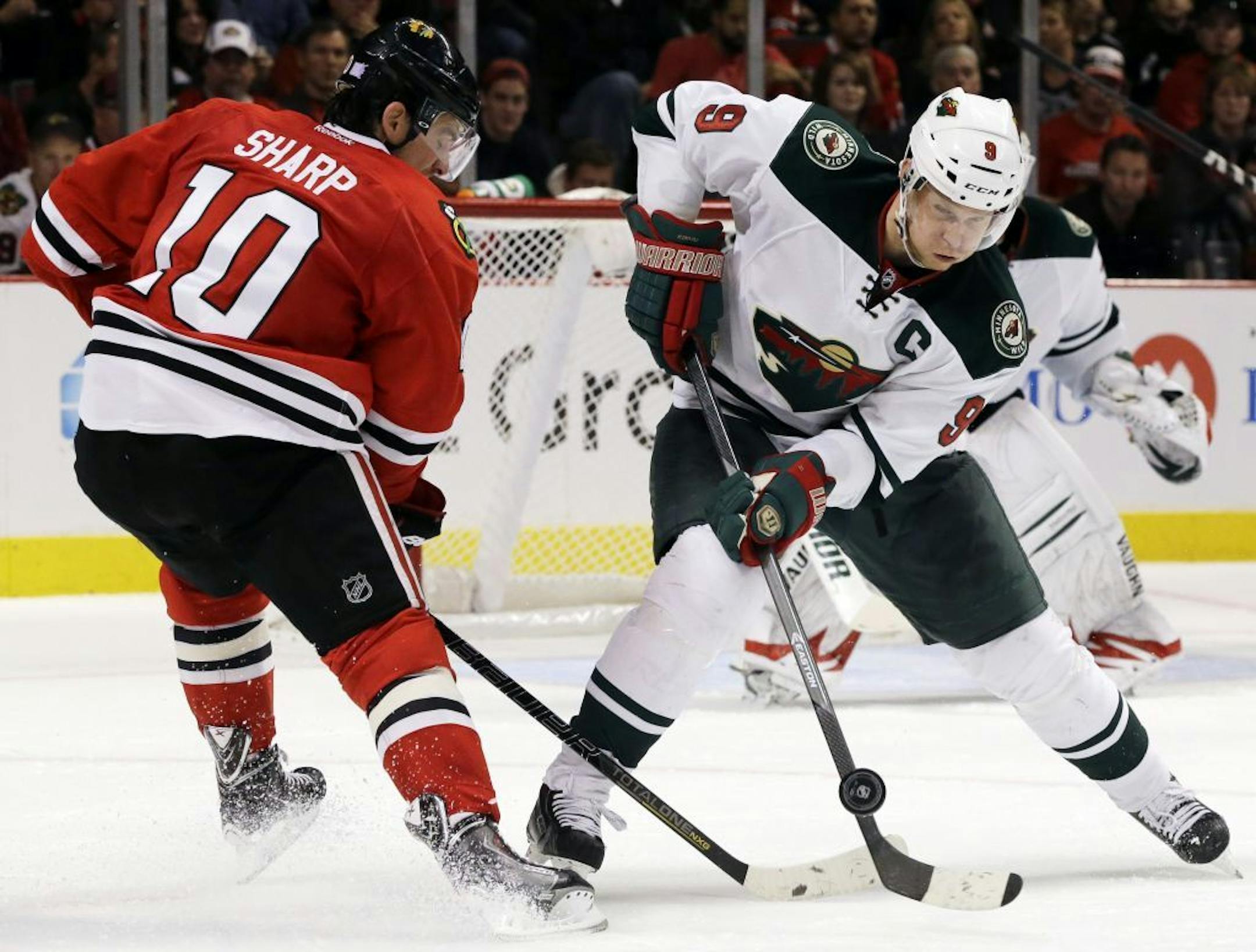 Minnesota Wild's Mikko Koivu (9) controls he puck against Chicago Blackhawks' Patrick Sharp (10) during the second period of an NHL hockey game in Chicago, Saturday, Oct. 26, 2013.