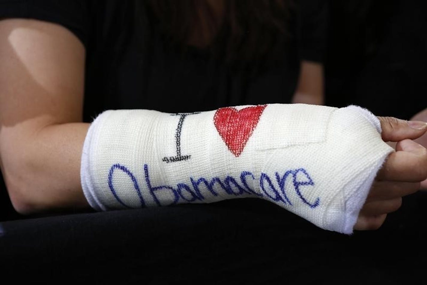 Cathey Park of Cambridge, Massachusetts wears a cast for her broken wrist with "I Love Obamacare" written upon it prior to U.S. President Barack Obama's arrival to speak about health insurance at Faneuil Hall in Boston October 30, 2013. REUTERS/Kevin Lamarque