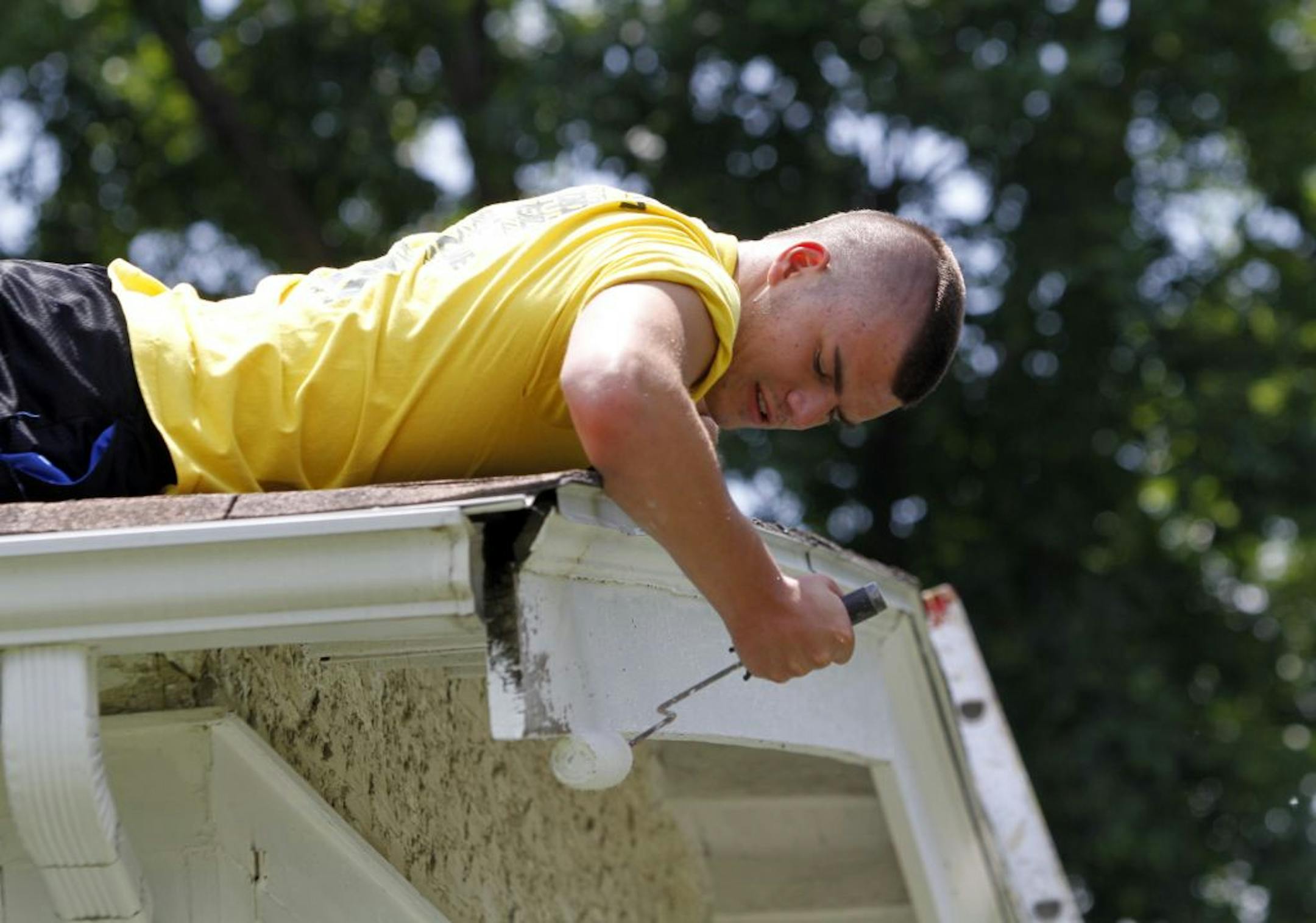 Paul Madison, a member of a volunteer crew from Catholic HEART Work Camp painted the exterior roof facia on Georgia Bredesen's house in Minneapolis.
