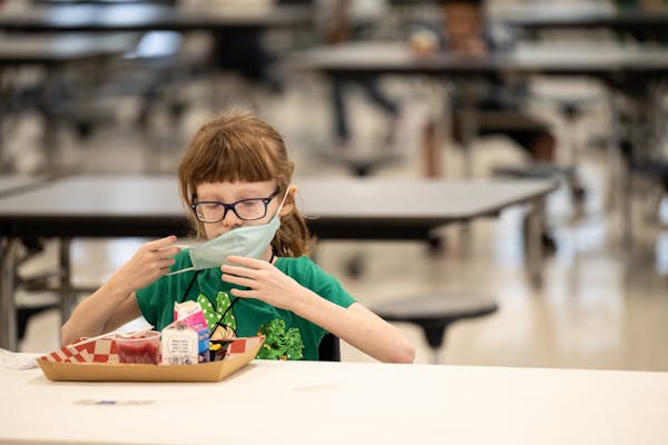 A child puts her mask back on after finishing lunch at a socially distanced table in the cafeteria of Medora Elementary School on March 17, 2021, in L