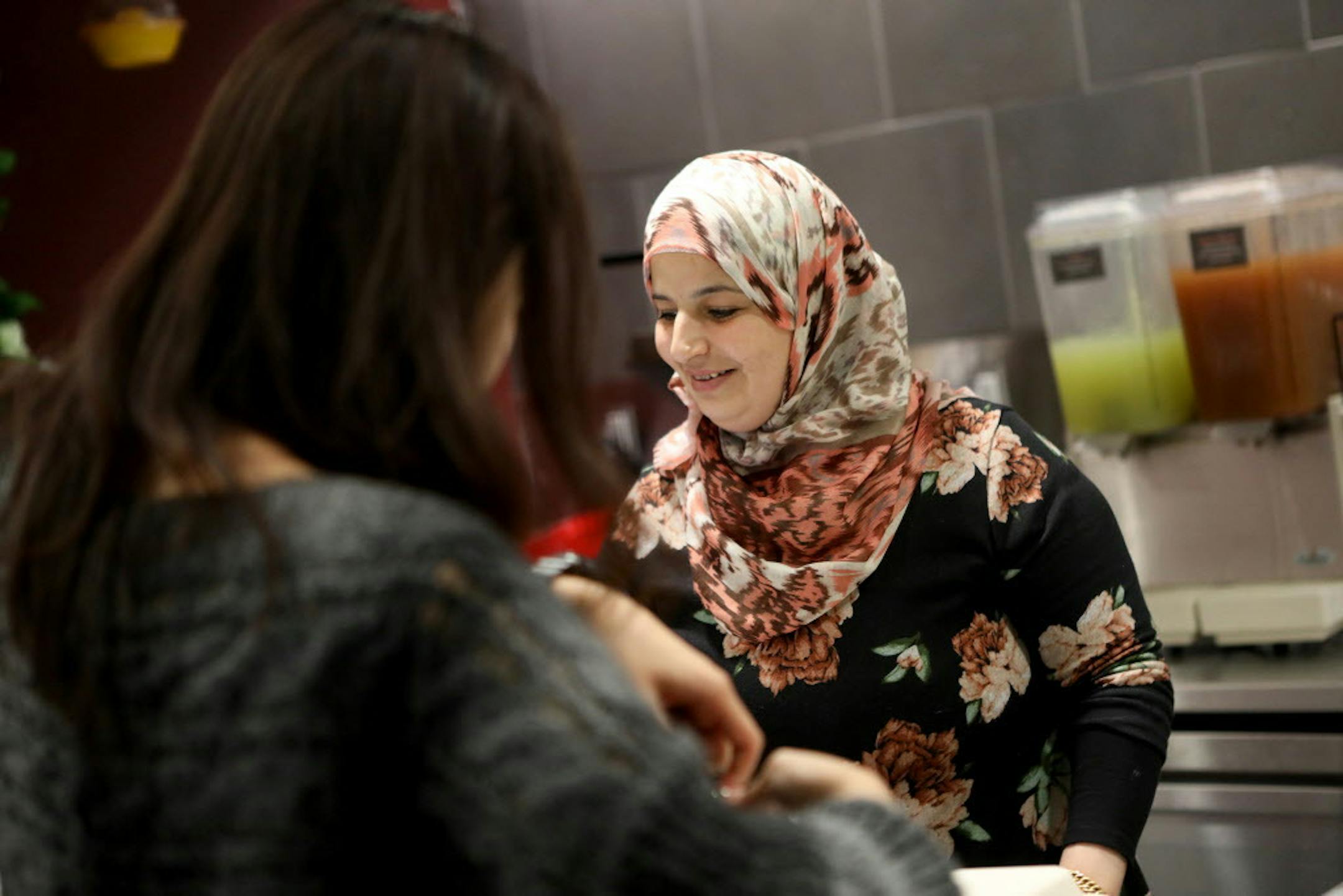 Rawaa Kasedah assists a customer at her food kiosk the Old Damascus Fare on the campus of UC Berkeley in Berkley, Calif., on Wednesday, Oct. 18, 2018. The Rawas family arrived in the United States as refugees in 2015, settling into Oakland to escape the traumas of Syria's civil war. Three years later, the family owns a catering business, Old Damascus Fare, that serves authentic Syrian food.