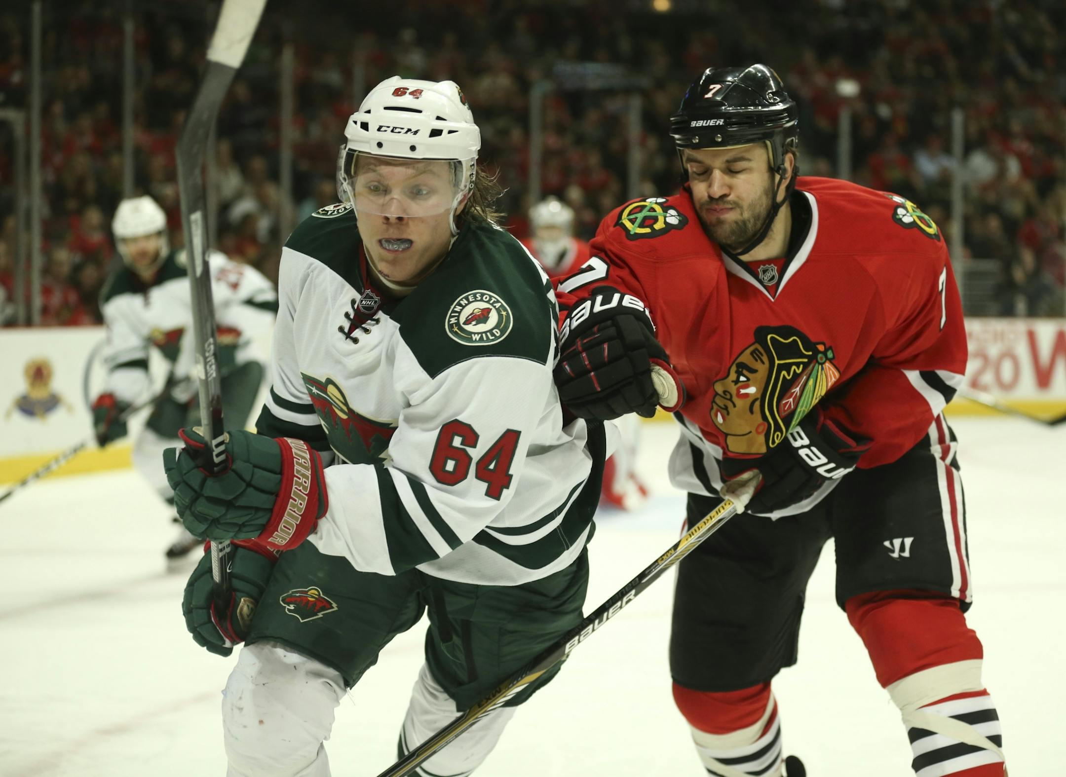 Minnesota Wild center Mikael Granlund (64) and Chicago Blackhawks defenseman Brent Seabrook (7) charged the puck against the boards in the third period Sunday afternoon at United Center in Chicago.