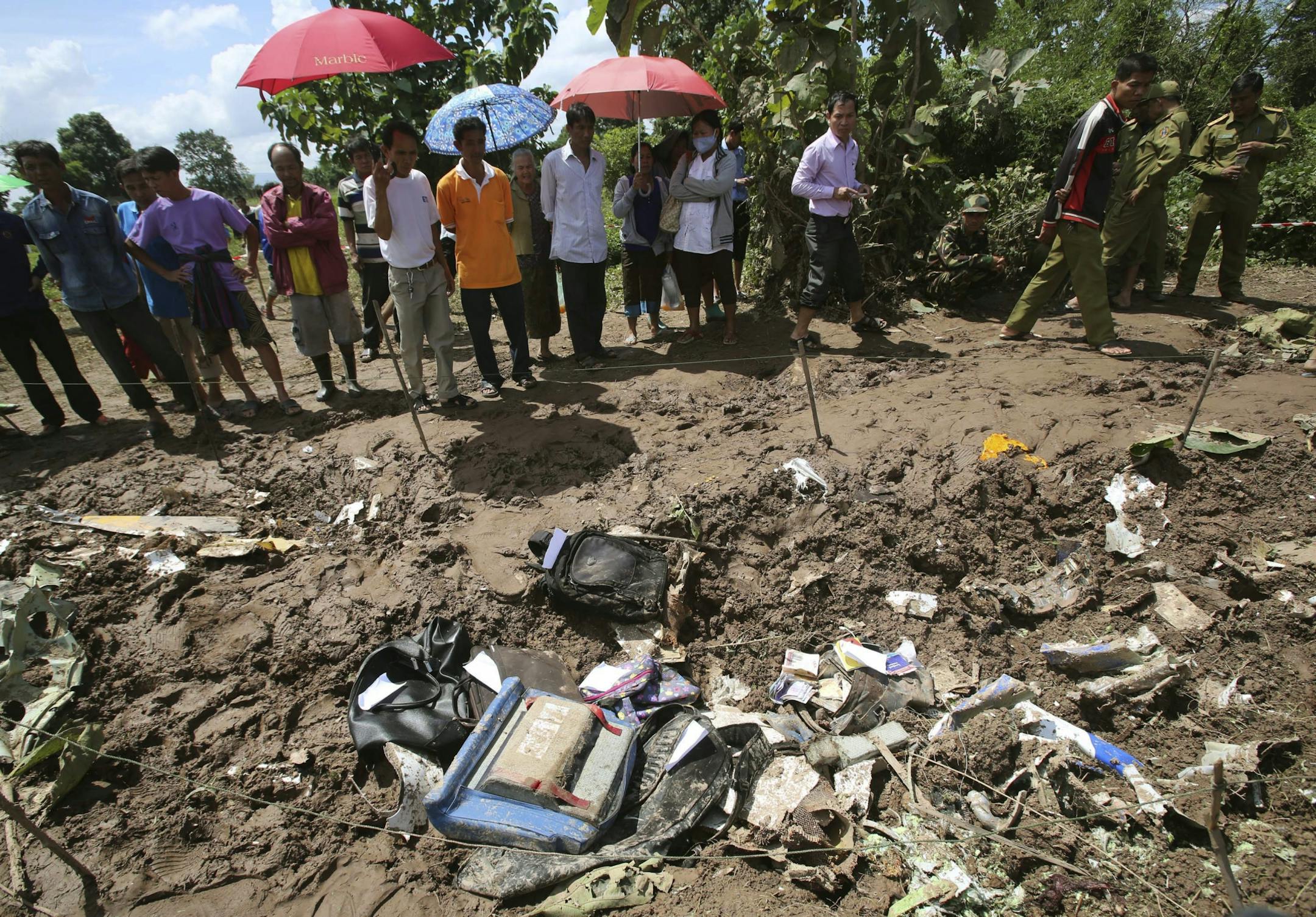 People look at the debris of a Lao Airlines turboprop plane that crashed into the Mekong River, in Pakse, Laos on Thursday, Oct. 17, 2013. Backpacks, an airplane propeller and passports were among the debris.