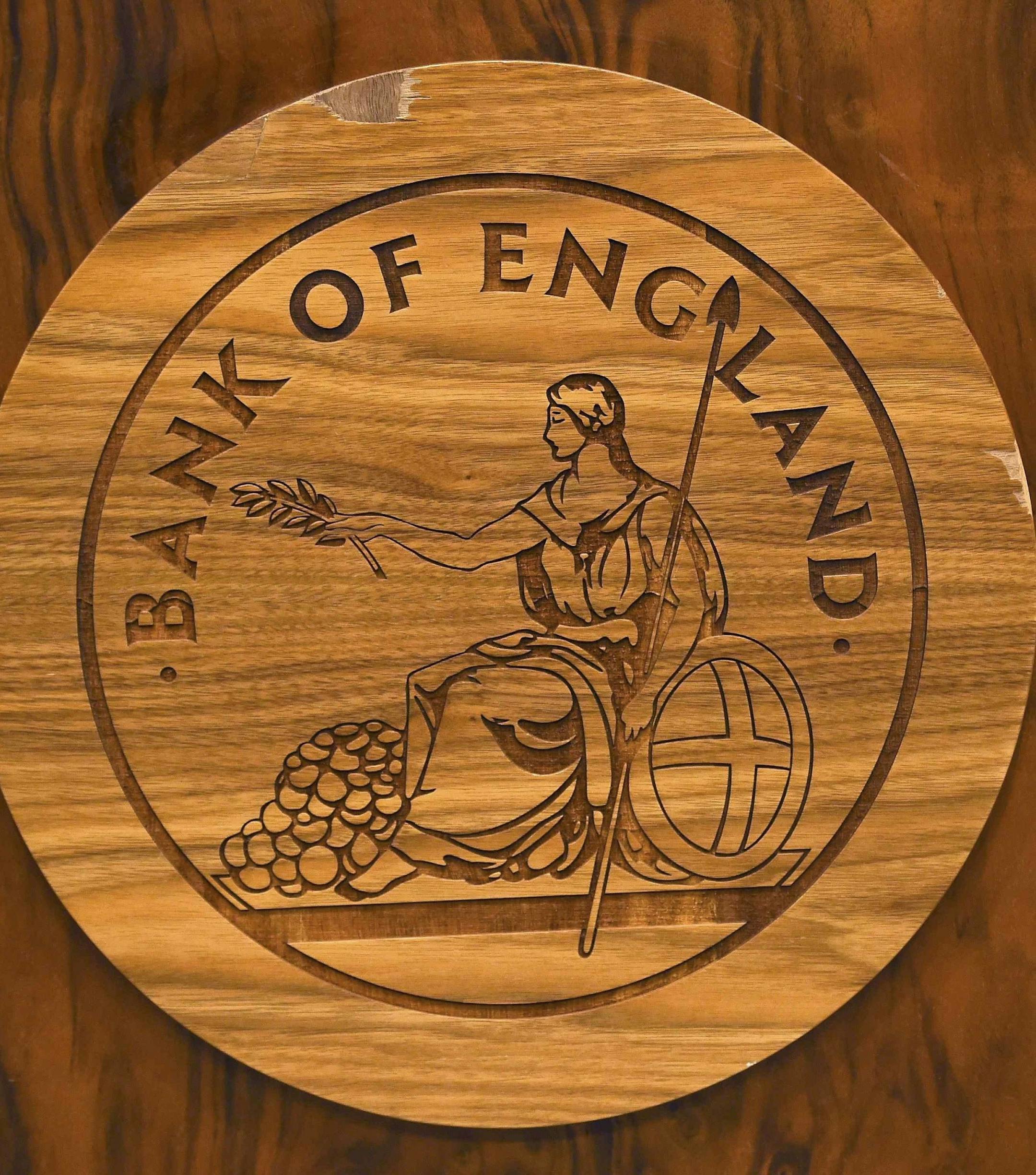 A wooden carving of the Bank of England logo is seen on a desk during a news conference by Bank of England governor Mark Carney at the Bank of England in London, Britain July 5, 2016. Carney says some of the risks predicted to the economy before the referendum on leaving the European Union have begun to crystalize, but that the institution will act to support jobs and growth. (Dylan Martinez/ Pool via AP)