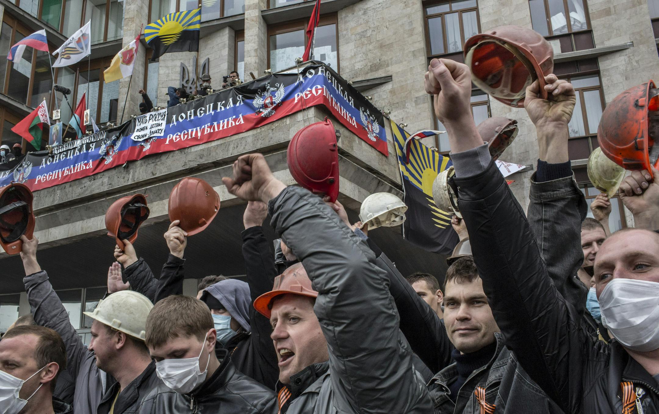 Coal miners raise their hard hats as they cheer pro-Russian demonstrators occupying the regional administrative building in Donetsk, Ukraine, April 10, 2014. The demonstrators occupying the building have declared the creation of the Donetsk People’s Republic, an imaginary state with no authority outside the building that a Russian-speaking, club-bearing crowd has occupied since Sunday. (Mauricio Lima/The New York Times)