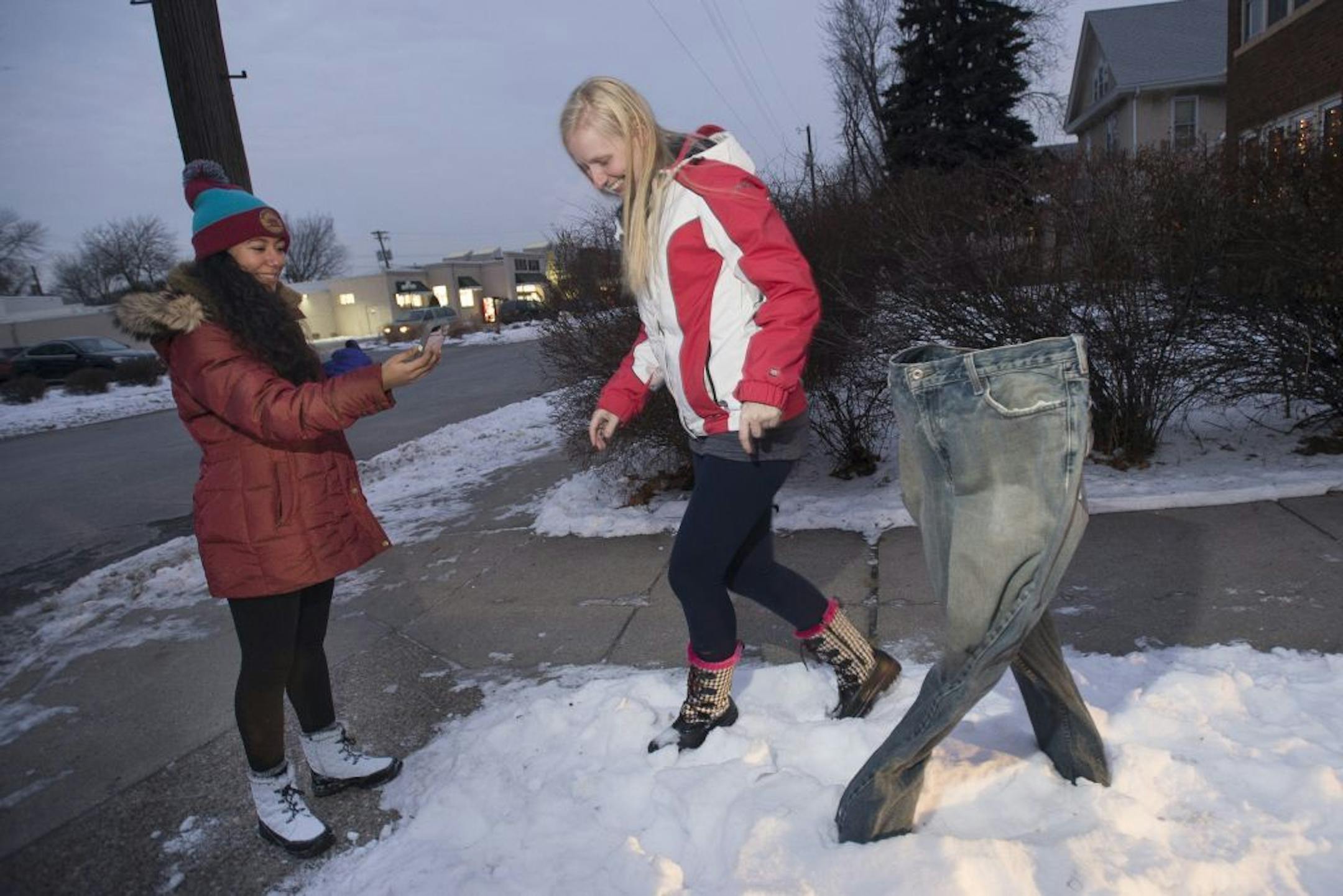 Melissa Valladires, visiting from El Salvador for an internship, left, and Kara Osgood, or Cottage Grove, took photos of each other in front of a pair of frozen blue jeans on display at the intersection of 16th Avenue Northeast and 2nd Street Northeast on Tuesday, Jan. 19, 2016 in Minneapolis, Minn. The jeans were put out by Randall Johnson, of Minneapolis, a former student of MCAD.