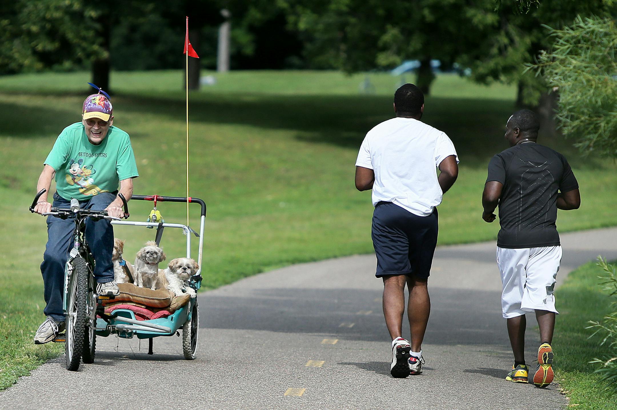 Marv Johnson made his way around Palmer Lake Park with his dogs, Chloe, Tootsie and Holly, during a morning bike ride, Tuesday, August 6, 2013 at Palmer Lake Park in Brooklyn Park, MN.(ELIZABETH FLORES/STAR TRIBUNE) ELIZABETH FLORES &#x2022; eflores@startribune.com