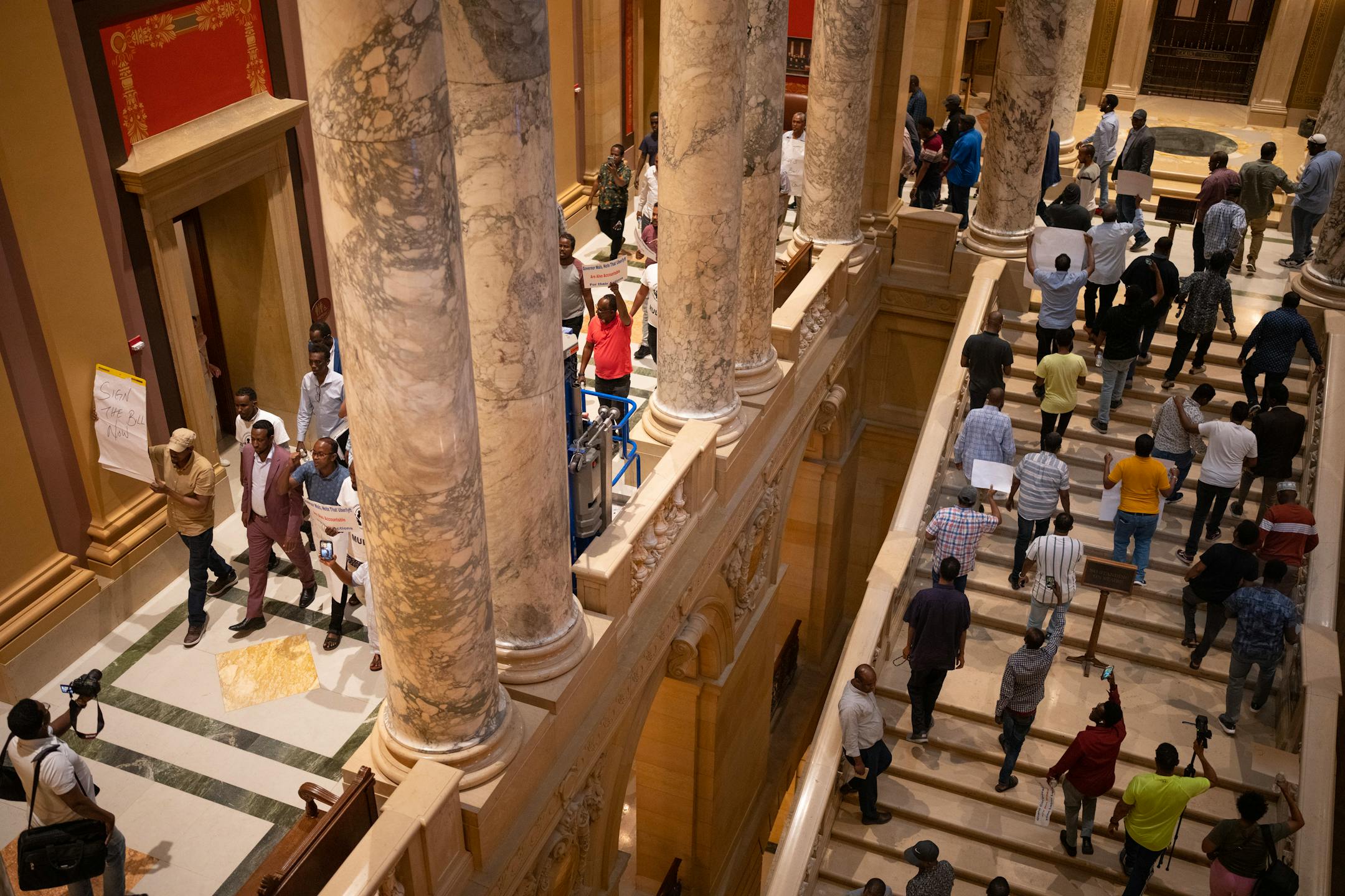Members of the Minnesota Uber Lyft Drivers Association chanted as they paraded through the halls of the State Capitol Monday night calling on Gov. Tim Walz to sign the bill that gives them a minimum wage and other benefits.