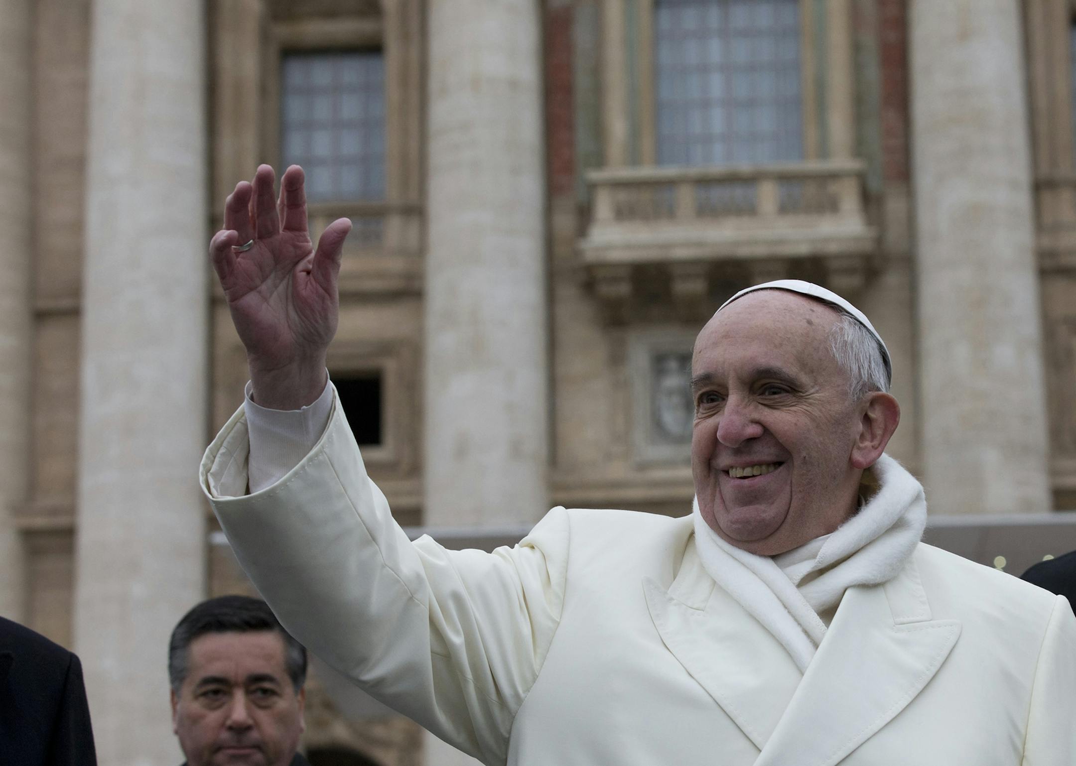 Pope Francis waves to faithful at the end of his weekly general audience in St. Peter's Square at the Vatican, Wednesday, Nov. 27, 2013. Francis has cheered the thousands of pilgrims who braved a cold snap belting Italy to attend his weekly general audience, saying they were courageous to come out. Francis himself was bundled up in a white double-breasted winter coat and scarf, but it wasn't enough. He had to use his sleeves as a muffler to keep his hands warm amid temperatures that on Wednesday