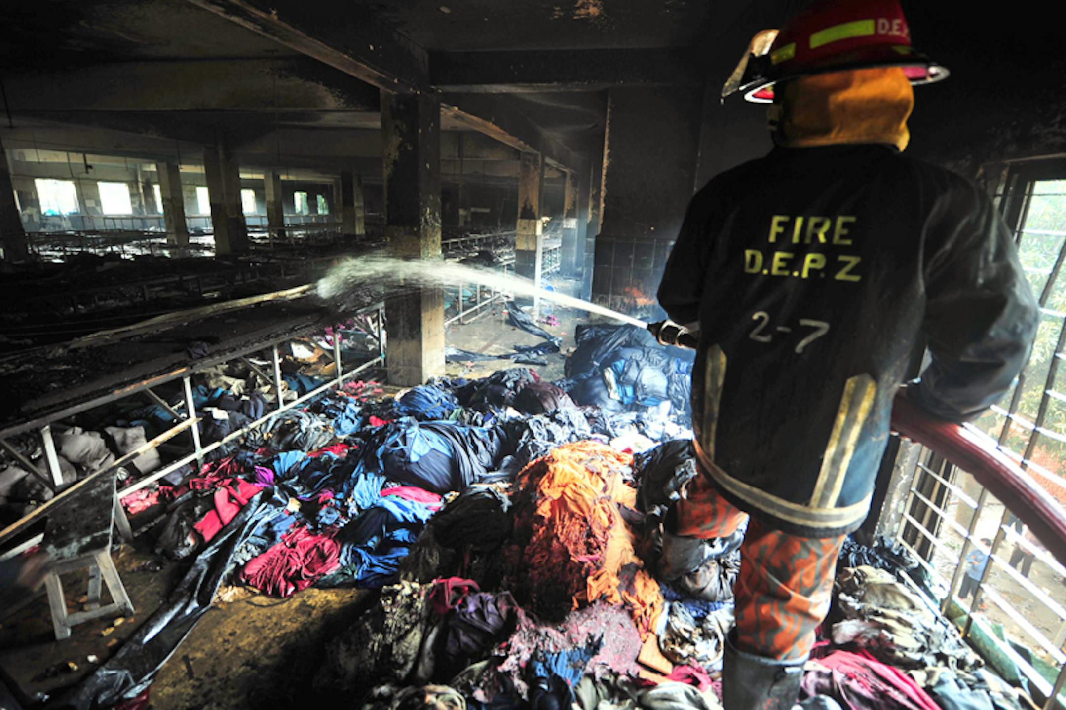 Nov. 25, 2012: A firefighter douses the inside of a burned out garment factory on the outskirts of Dhaka, Bangladesh where 112 workers were killed.