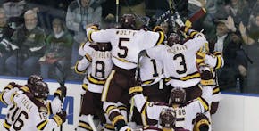 Minnesota-Duluth players surround Adam Johnson after his goal during overtime of the NCAA West Regional college hockey final against Boston University