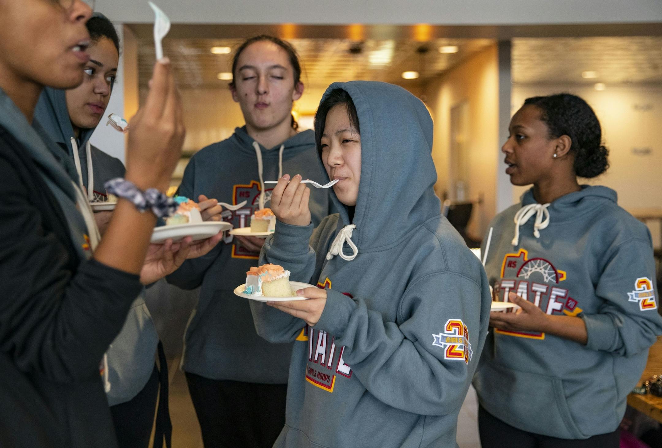 Duluth Marshall girl's basketball team players enjoyed pieces of cake that were brought out to celebrate the team after they were forced to return home early following the cancellation of the MSHL girl's basketball tournament.