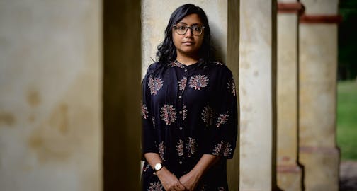 photo of author Megha Majumdar, standing in front of a pillar