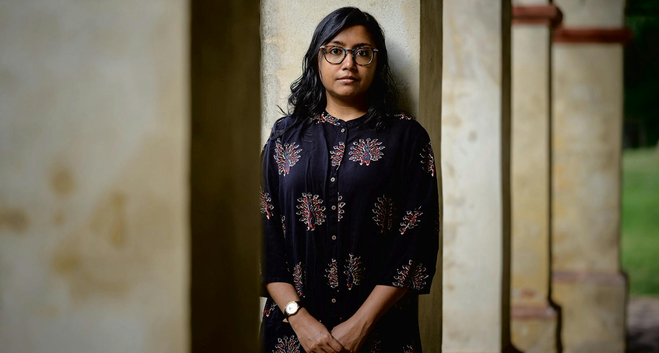 photo of author Megha Majumdar, standing in front of a pillar