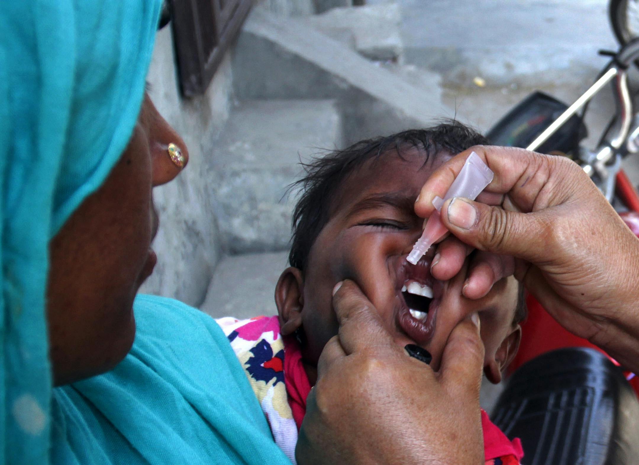 A Pakistani health worker gives a child a polio vaccine in Lahore, Pakistan, Monday, May 5, 2014. For the first time, the World Health Organization on Monday declared the spread of polio an international public health emergency that could grow in the next few months and unravel the nearly three-decade effort to eradicate the crippling disease. (AP Photo/K.M. Chaudary)