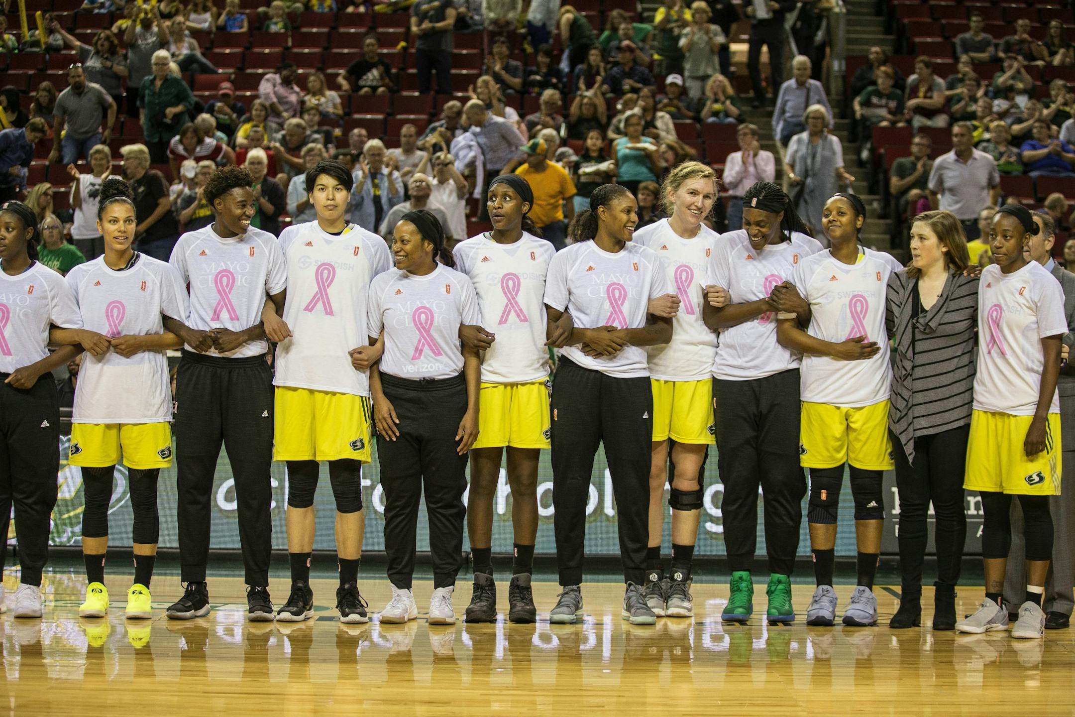 Players from the Seattle Storm and the Minnesota Lynx join arms for a moment of silence for Heather Heyer, who was killed in Charlottesville, Va., this past weekend, before a WNBA basketball game Wednesday, Aug. 16, 2017, in Seattle.
