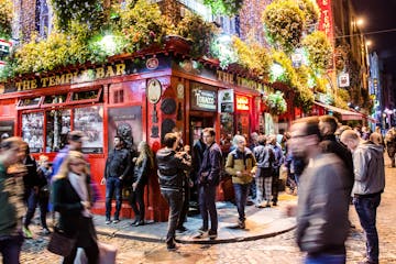 Long exposure of Temple bar in Dublin with people drinking and walking by during night in autumn