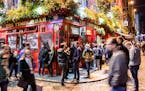 Long exposure of Temple bar in Dublin with people drinking and walking by during night in autumn