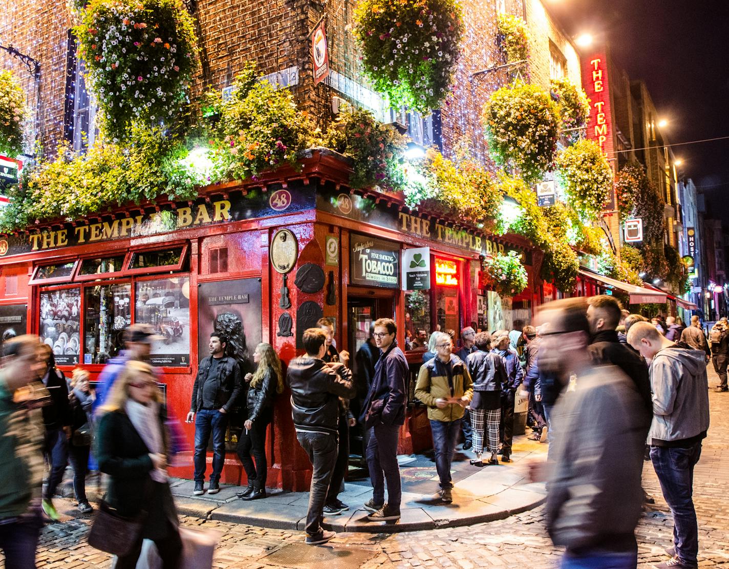 Long exposure of Temple bar in Dublin with people drinking and walking by during night in autumn