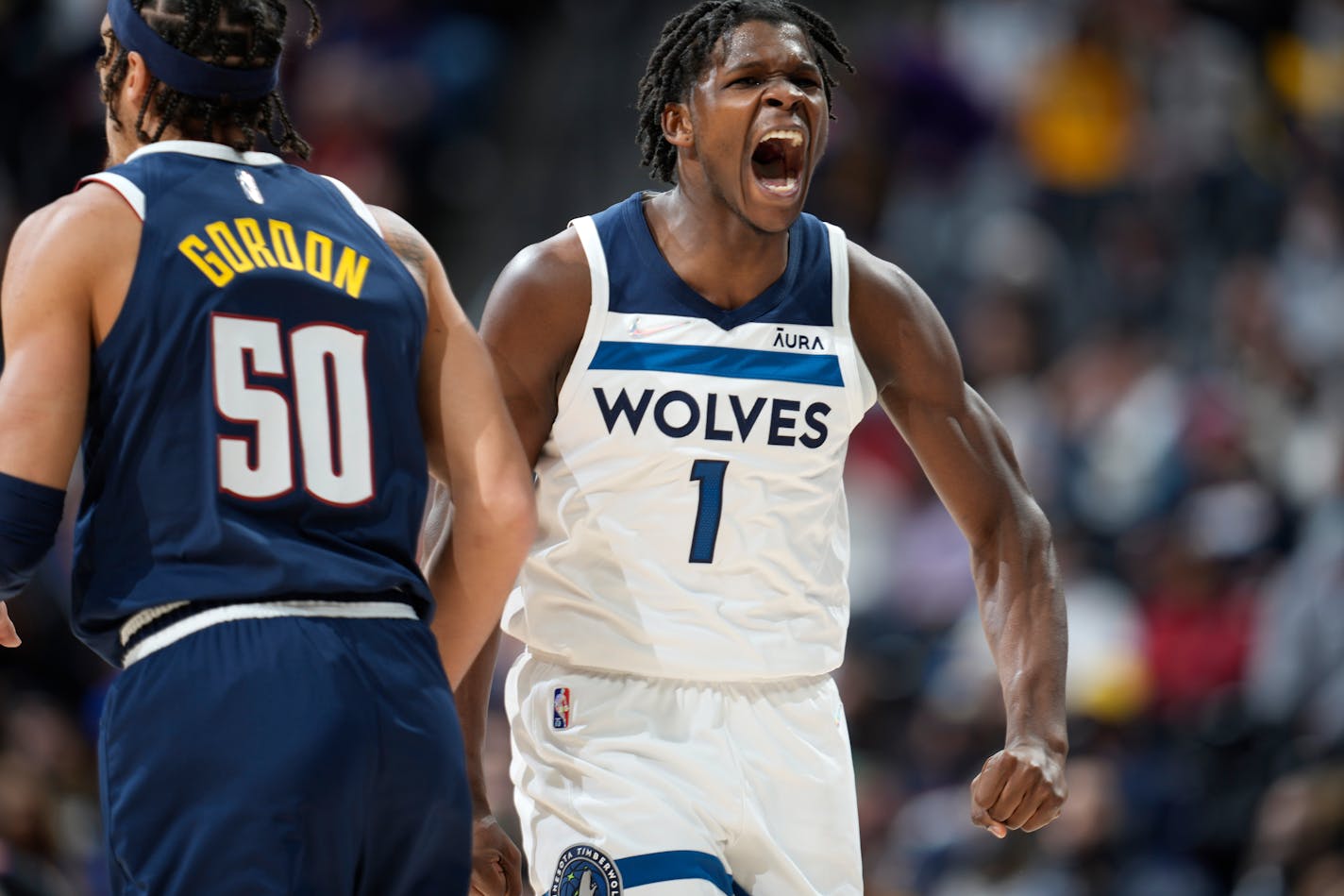 Minnesota Timberwolves forward Anthony Edwards, right, reacts after hitting a 3-point-basket over Denver Nuggets forward Aaron Gordon in the second half of an NBA basketball game Wednesday, Dec. 15, 2021, in Denver. The Timberwolves won 124-107. (AP Photo/David Zalubowski)