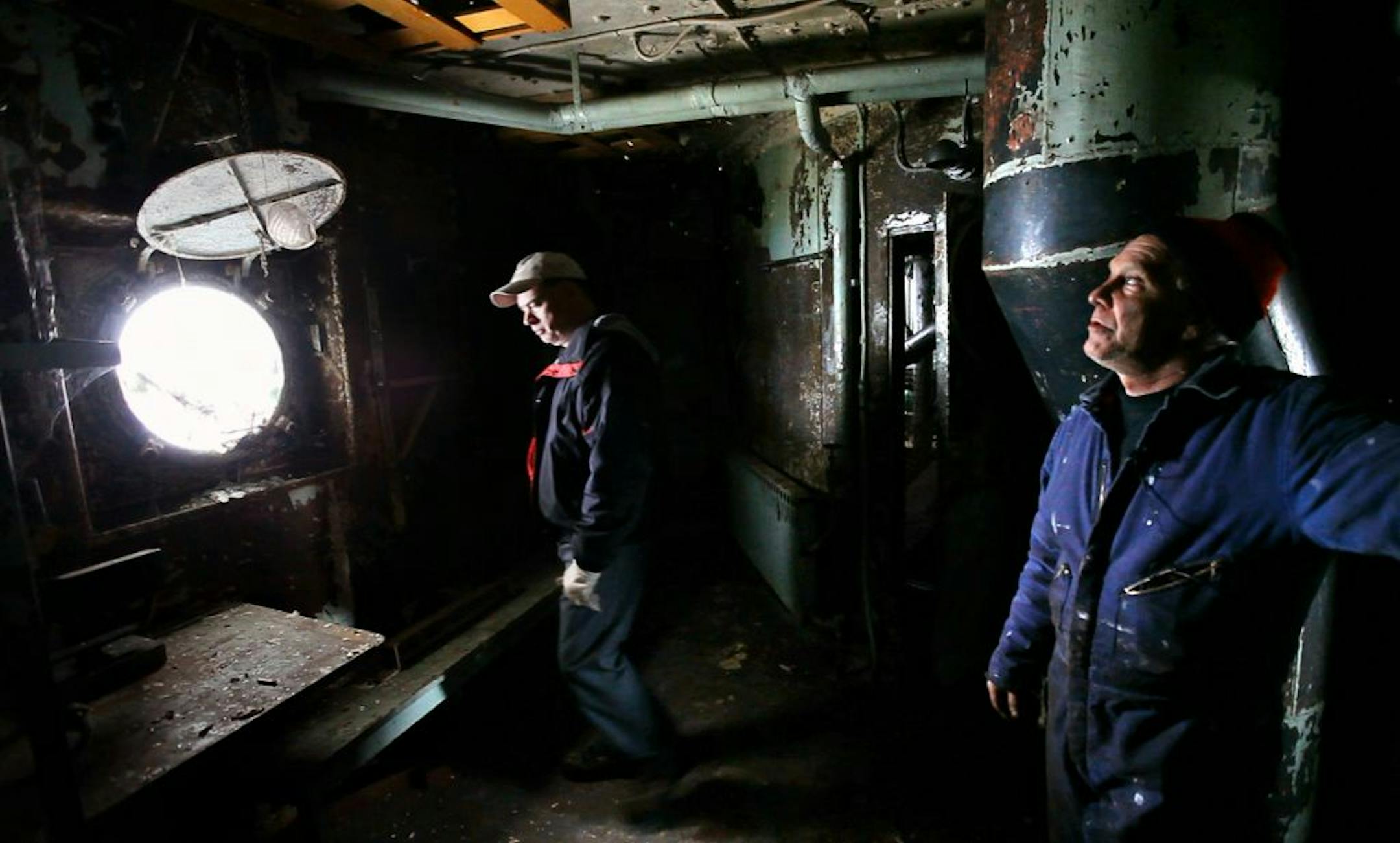 Restoration project manager Phil Kerber, left, and Bob Olson examined crew quarters that have yet to be restored on the S.S. Meteor. Rust, flaking paint and cobwebs cover the space.