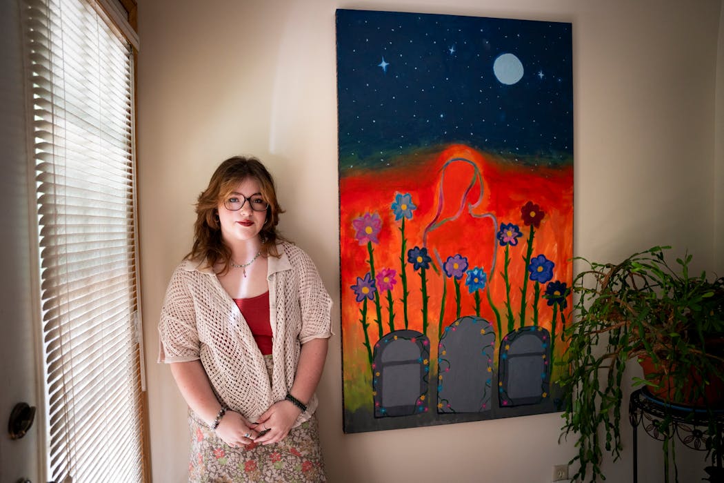 Nora Strande stands beside a painting she made in honor of her late sister Amara.