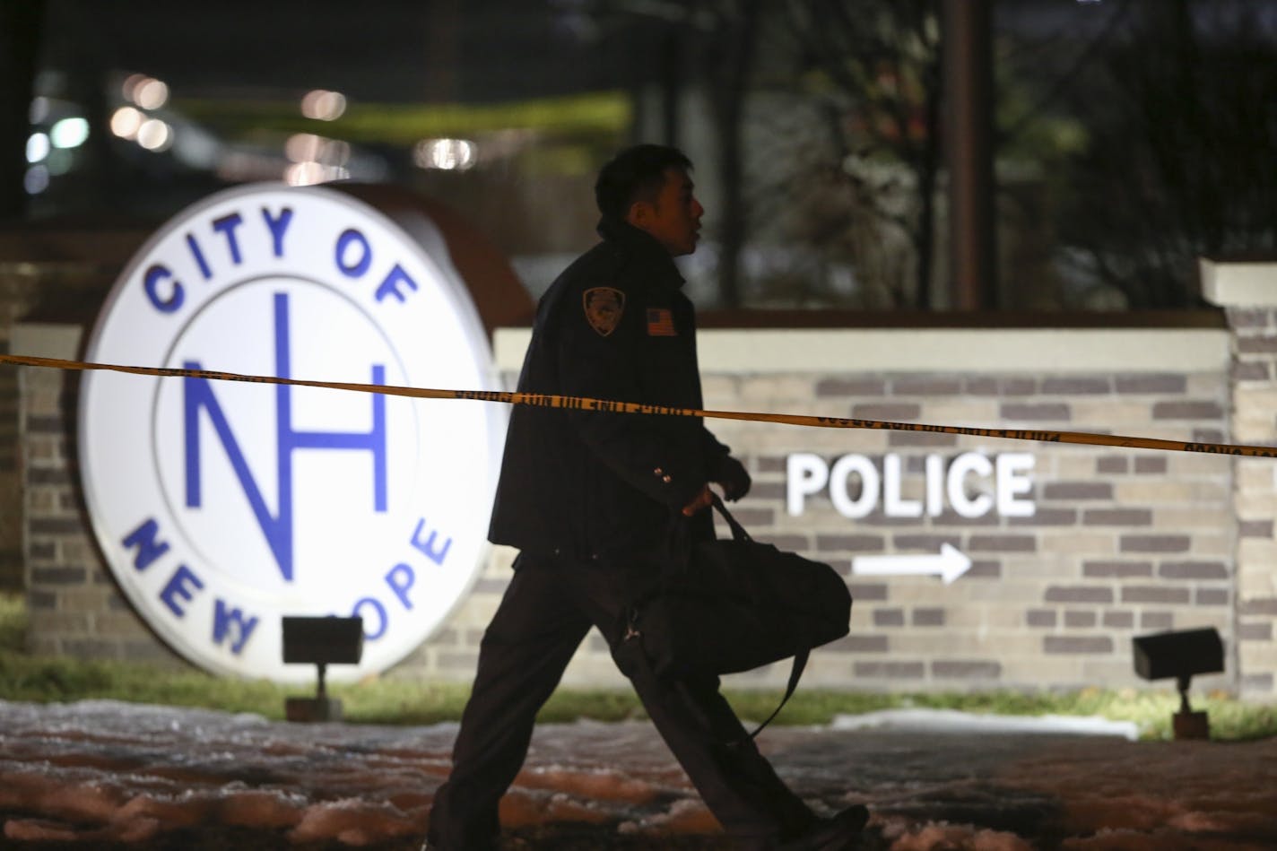 An emergency personnel member walks outside the New Hope Police Department after two police officers were shot Monday, Jan. 26, 2015 in New Hope, Minn. Two newly sworn-in officers and others were shot at Monday night as they left a New Hope City Council meeting. Two officers were hit, and others returned fire and killed the gunman, Hennepin County Sheriff's Chief Deputy Mike Carlson said. Authorities are not seeking any other suspects and did not identify the gunman or disclose a possible motive