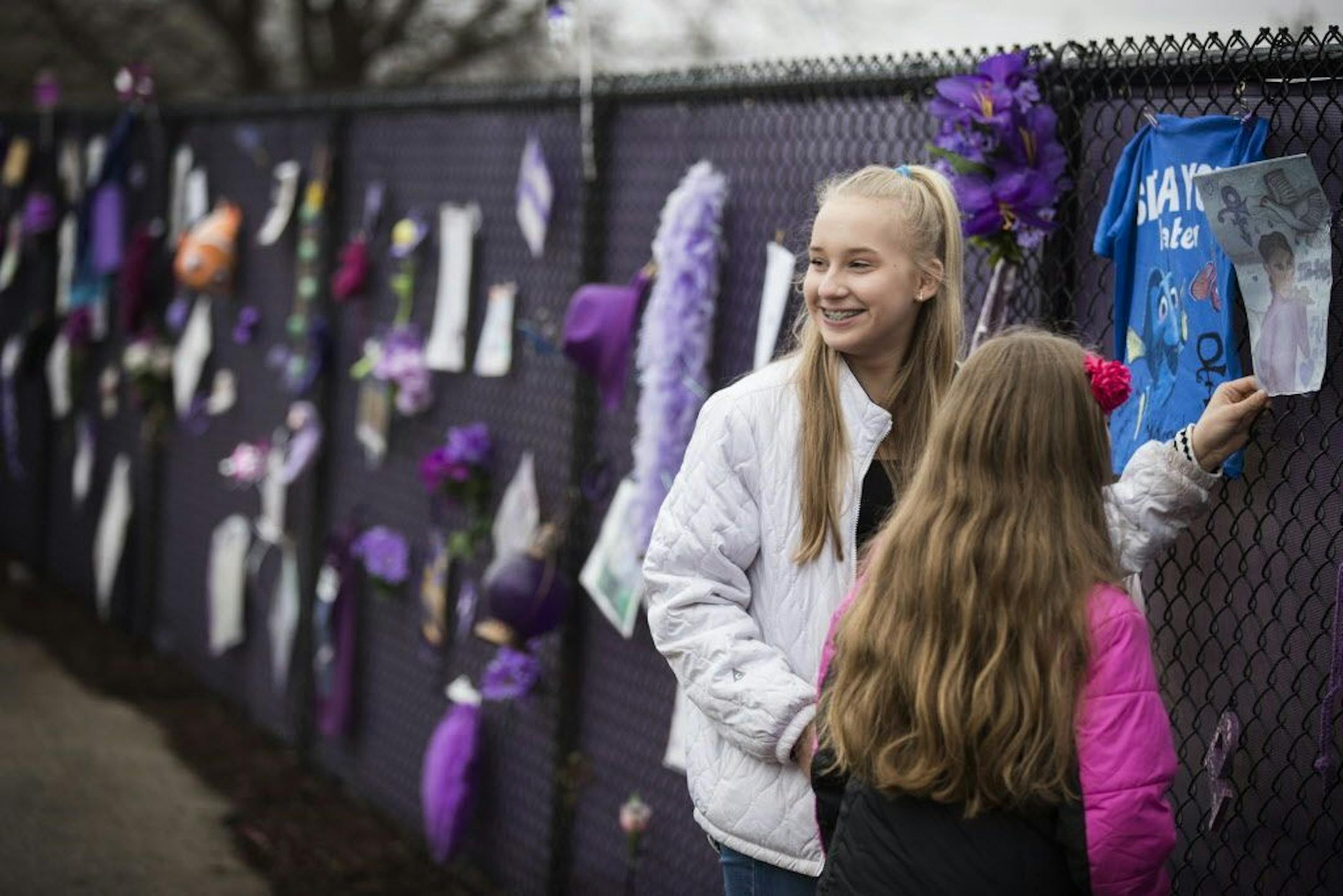 Anessa Reisinger, 13, of Excelsior puts a drawing on the "Prince4Ever" fence.