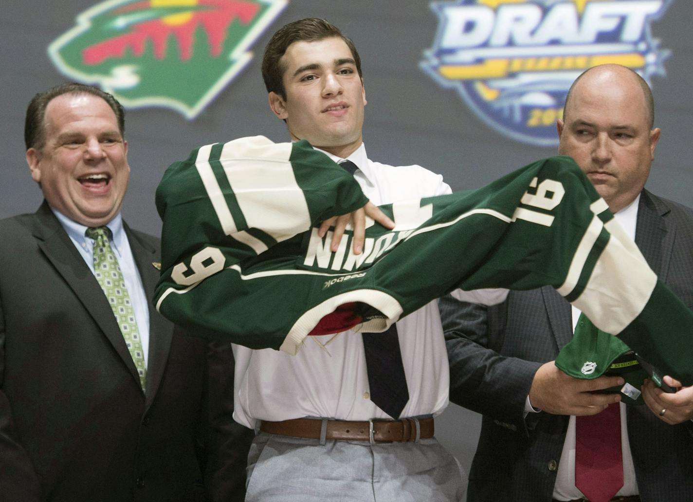 Luke Kunin, second from right, puts on his sweater as he stands with members of the Minnesota Wild management team at the NHL draft in Buffalo, N.Y., Friday June 24, 2016. (Nathan Denette/The Canadian Press via AP) MANDATORY CREDIT