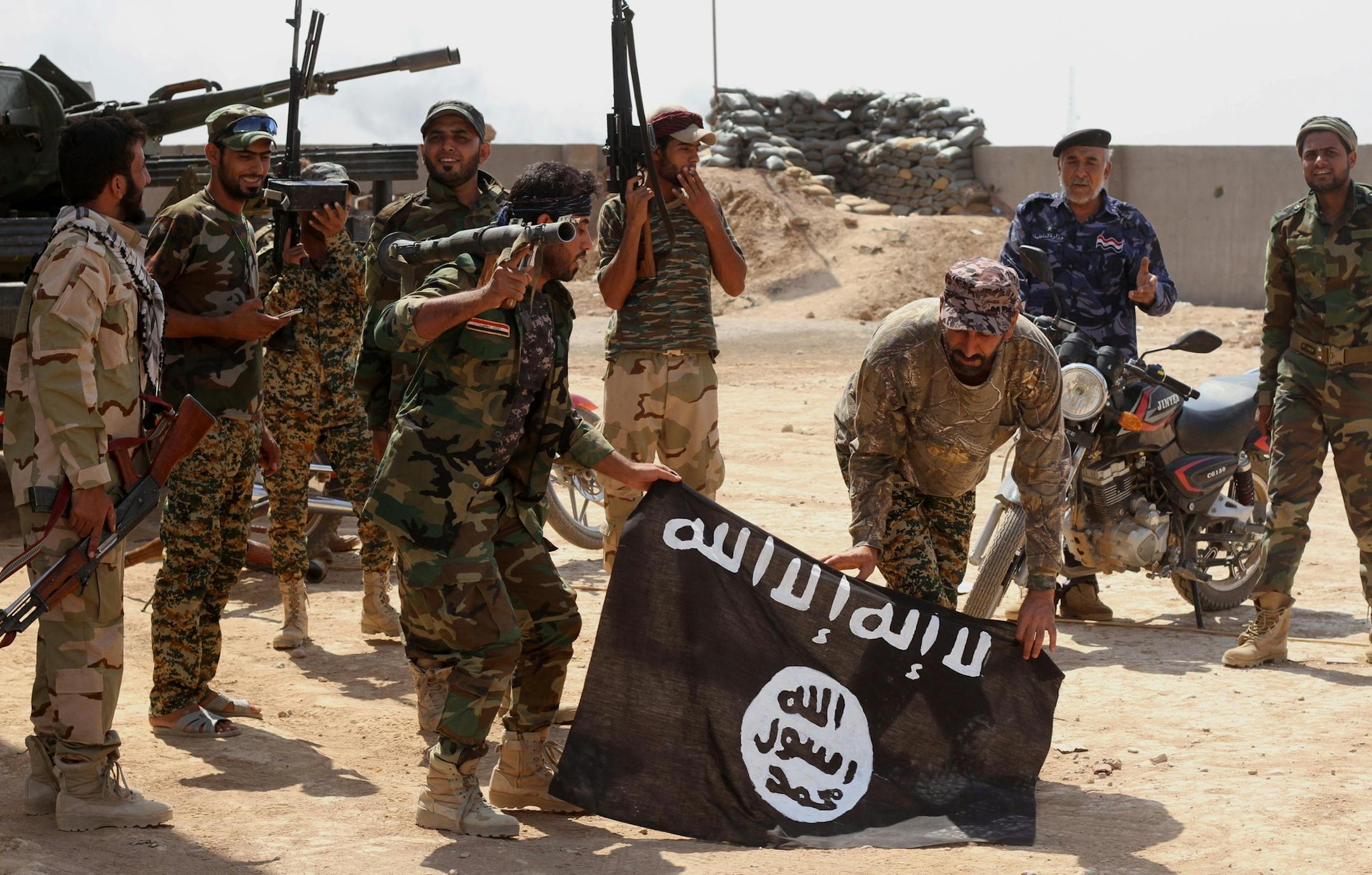 Iraqi security forces hold a flag of the Islamic State group they captured during an operation outside Amirli, some 105 miles (170 kilometers) north of Baghdad, Iraq, Monday, Sept. 1, 2014. Aid began flowing into the small northern Shiite town in Iraq on Monday, a day after security forces backed by Iran-allied Shiite militias and U.S. airstrikes broke a two-month siege by insurgents in a rare victory by government forces. (AP Photo)