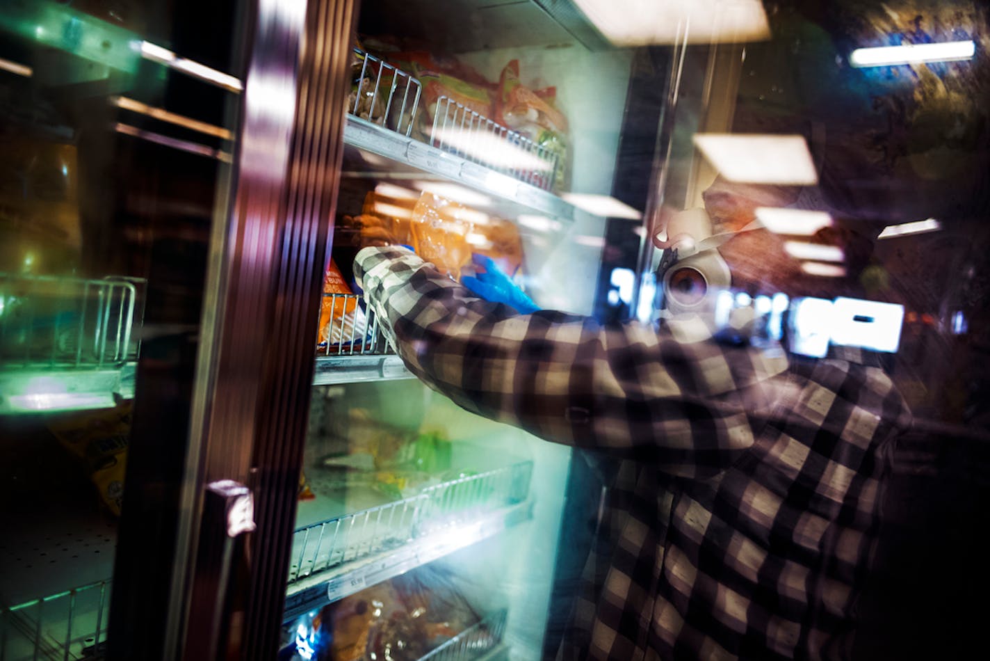 An employee at United Noodle stocks the frozen dumplings section in April while wearing a respirator mask, which is required of all store employees.