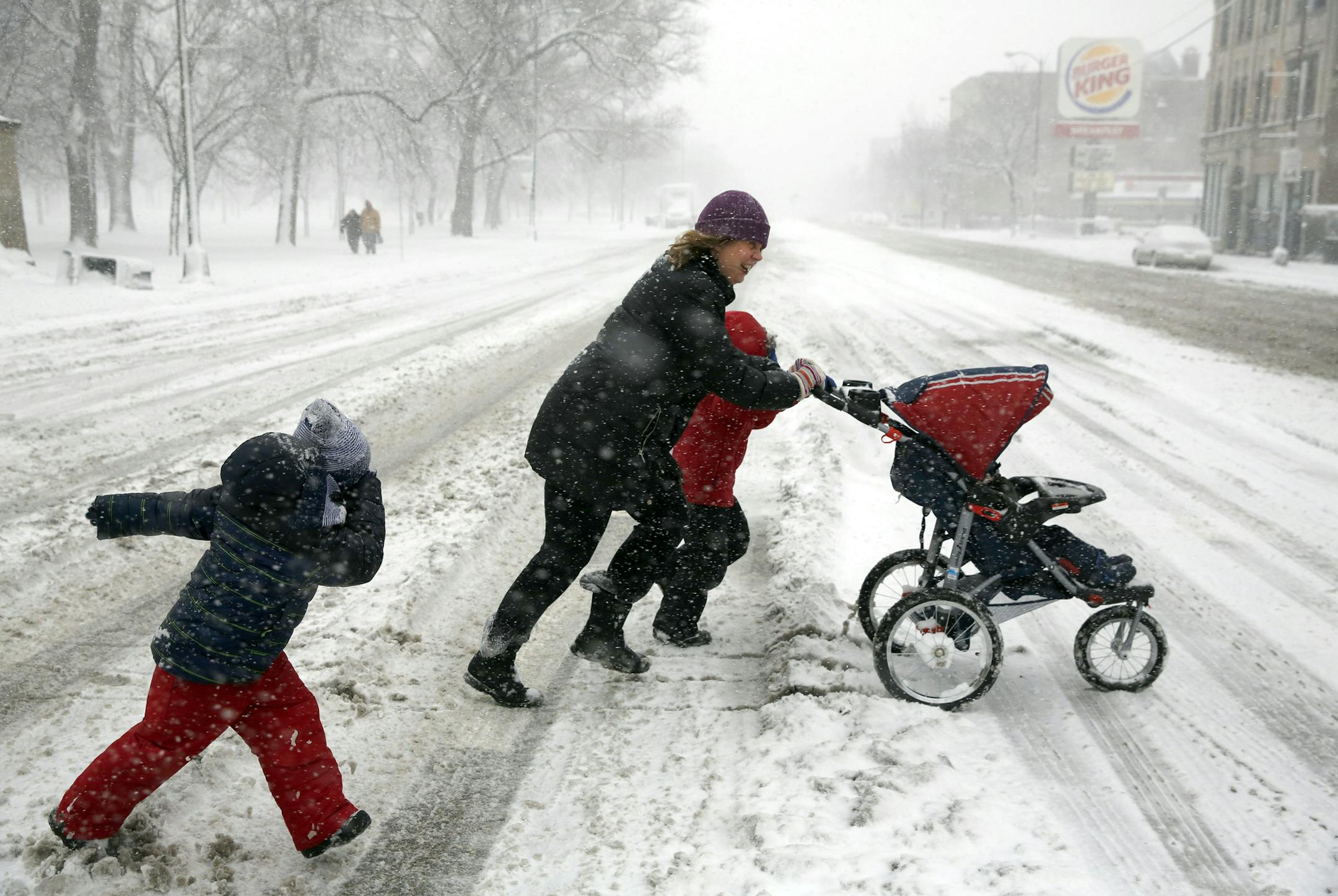 Christie Capshaw runs across North Avenue at California Avenue with her son James, 5, neighbor Sebastian, 4, and son William, 1, from left, Sunday Feb. 1, 2015, in Chicago's Humboldt Park.