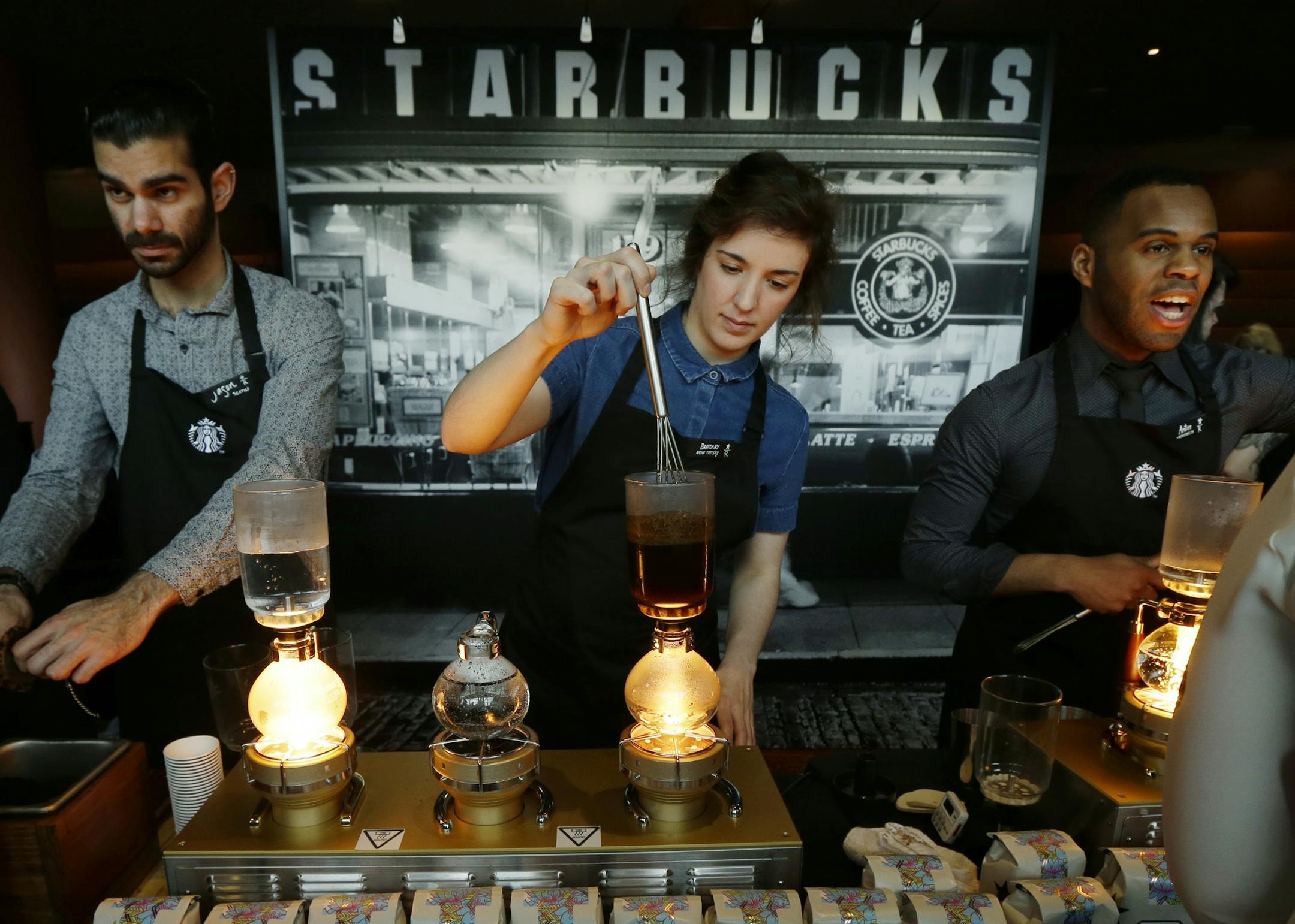 FILE - In this Wednesday, March 23, 2016, file photo, Starbucks workers prepare coffee using siphon vacuum coffee makers at a station in the lobby of the coffee company's annual shareholders meeting in Seattle. Starbucks says that it will be boosting the base pay of all employees and store managers at U.S. company-run stores by 5 percent or more on Oct. 3. In a letter sent to workers on Monday, July 11, 2016, CEO Howard Schultz said that the amount of the raise will be determined by geographic a