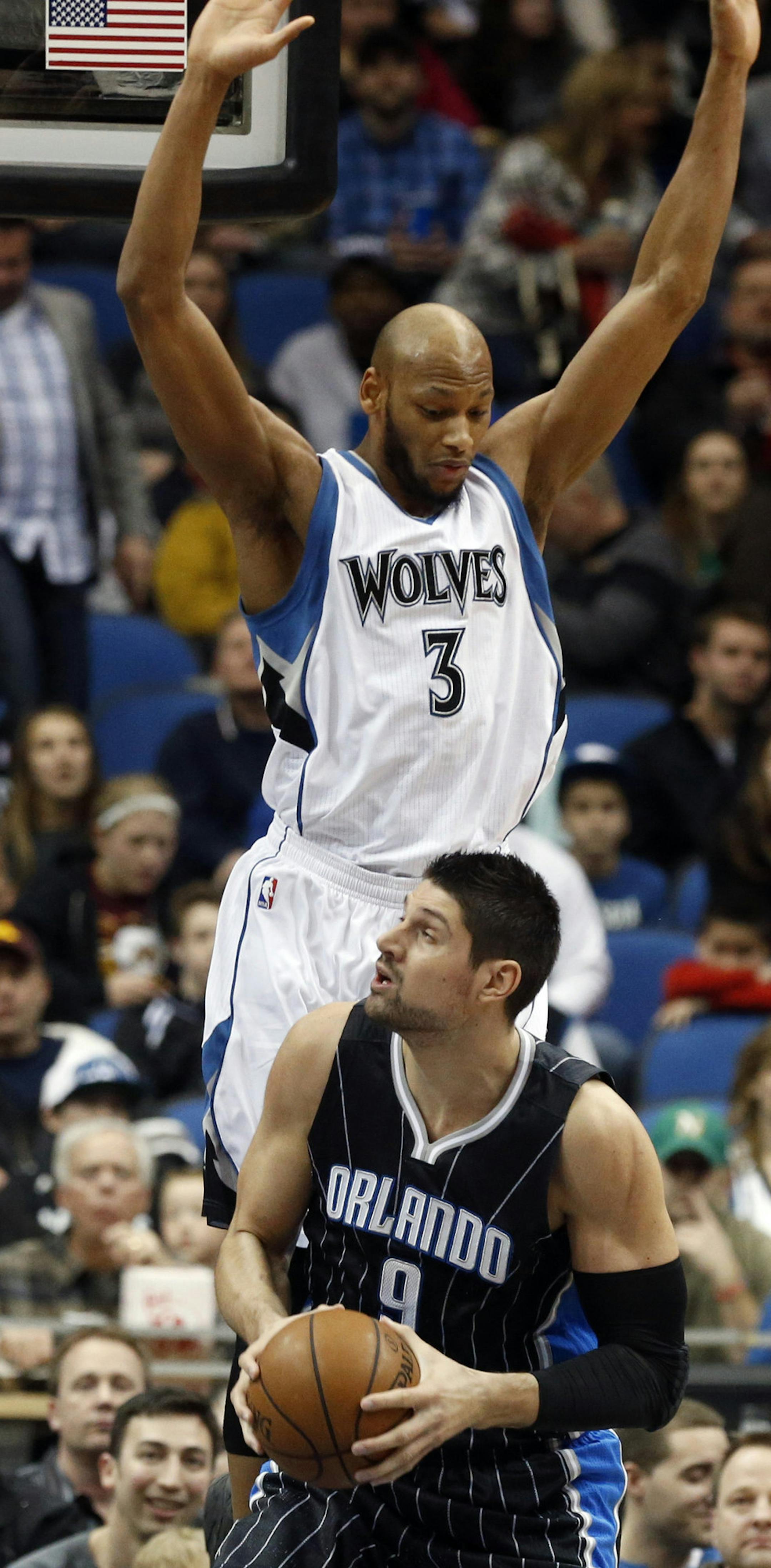Orlando Magic’s Nikola Vucevic, right, of Montenegro, eyes the basket as Minnesota Timberwolves' Adreian Payne hovers over him in the first quarter of an NBA basketball game, Friday, April 3, 2015, in Minneapolis. (AP Photo/Jim Mone)