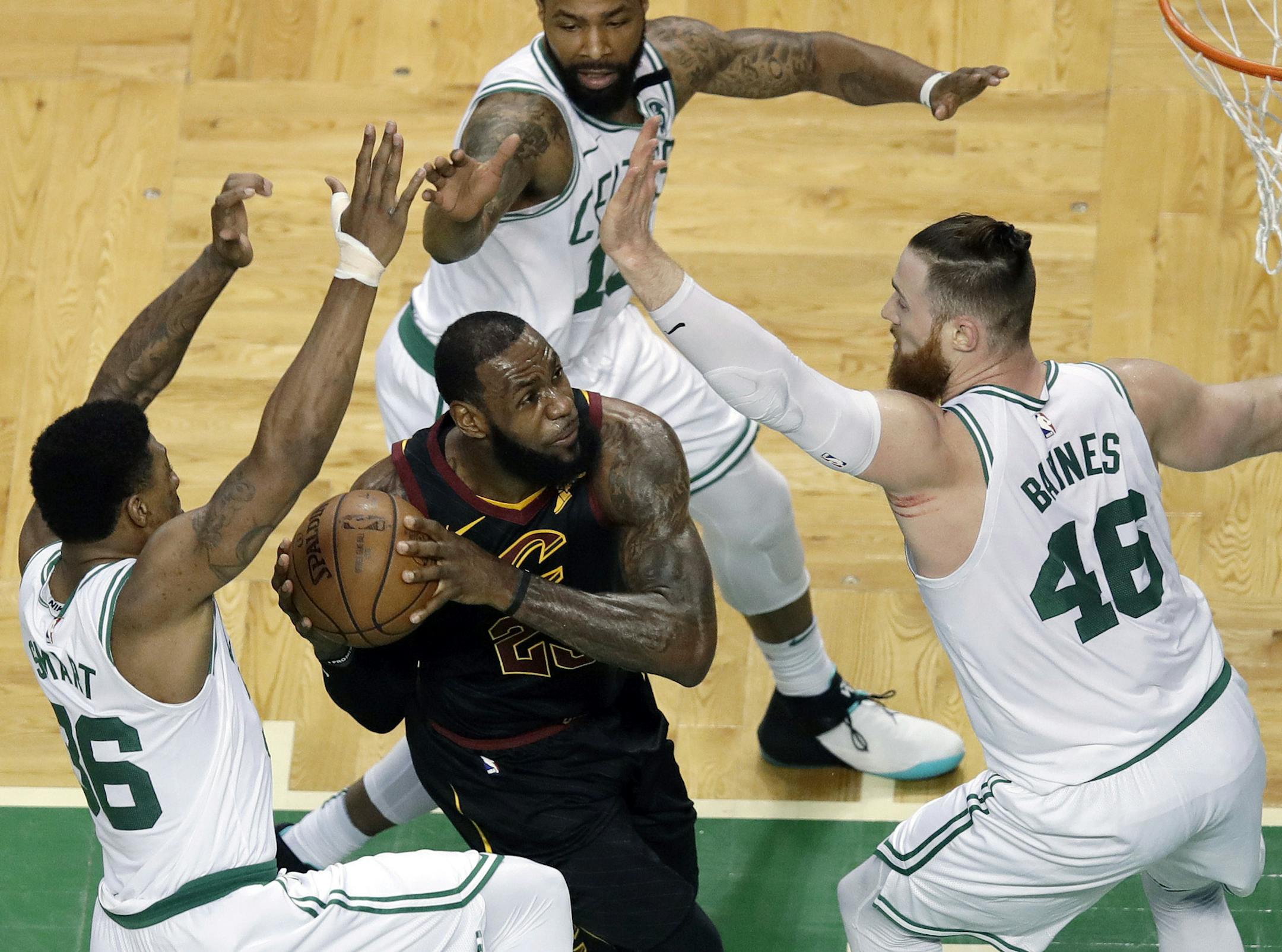 Cleveland Cavaliers forward LeBron James, center, drives through the defense of Boston Celtics guard Marcus Smart, left, forward Marcus Morris, rear, and center Aron Baynes, right, during the first half in Game 7 of the NBA basketball Eastern Conference finals, Sunday, May 27, 2018, in Boston. (AP Photo/Charles Krupa)