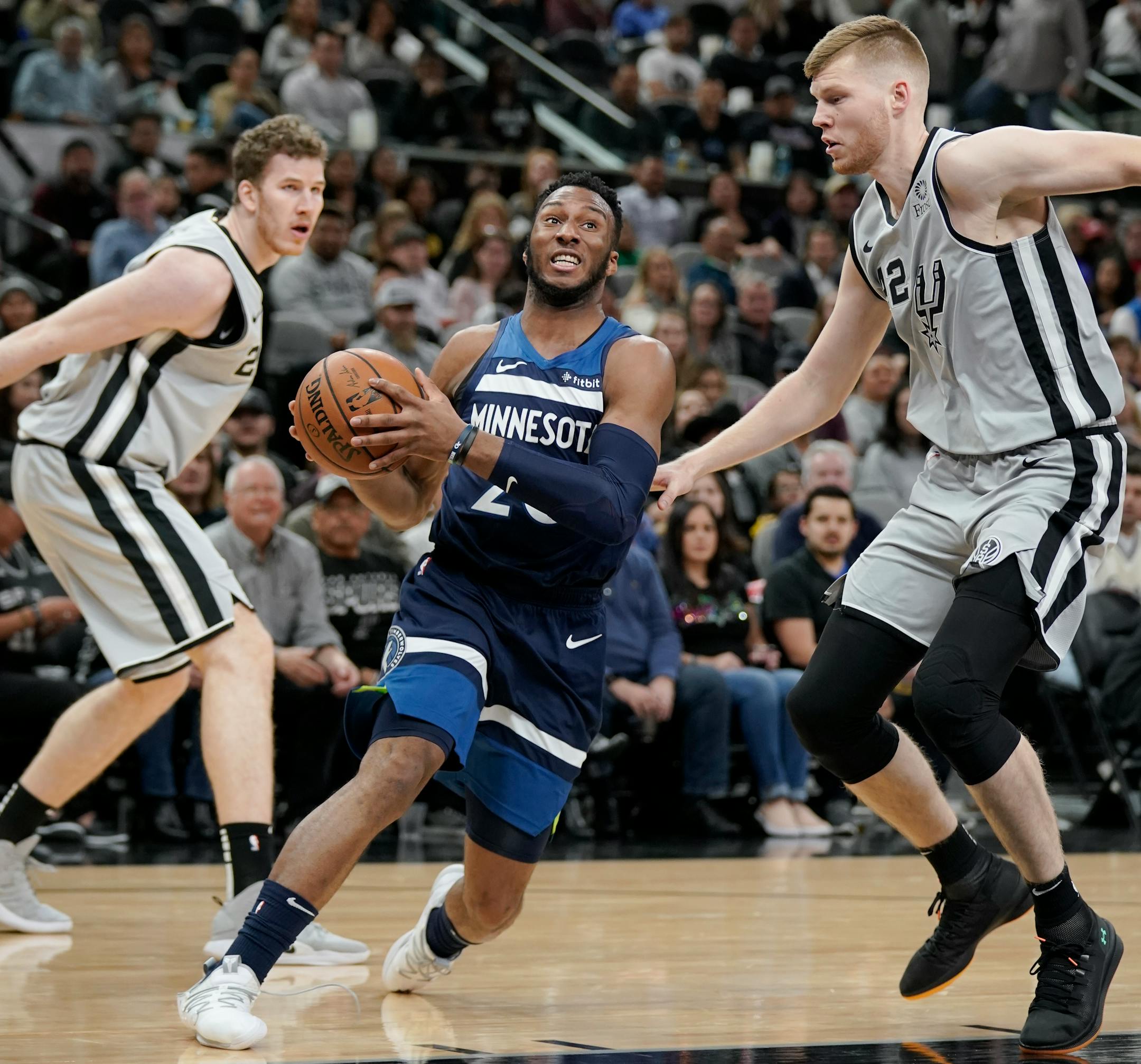 Minnesota Timberwolves' Josh Okogie, center, drives between San Antonio Spurs' Davis Bertans, right, and Jakob Poeltl during the first half of an NBA basketball game, Friday, Dec. 21, 2018, in San Antonio. (AP Photo/Darren Abate)