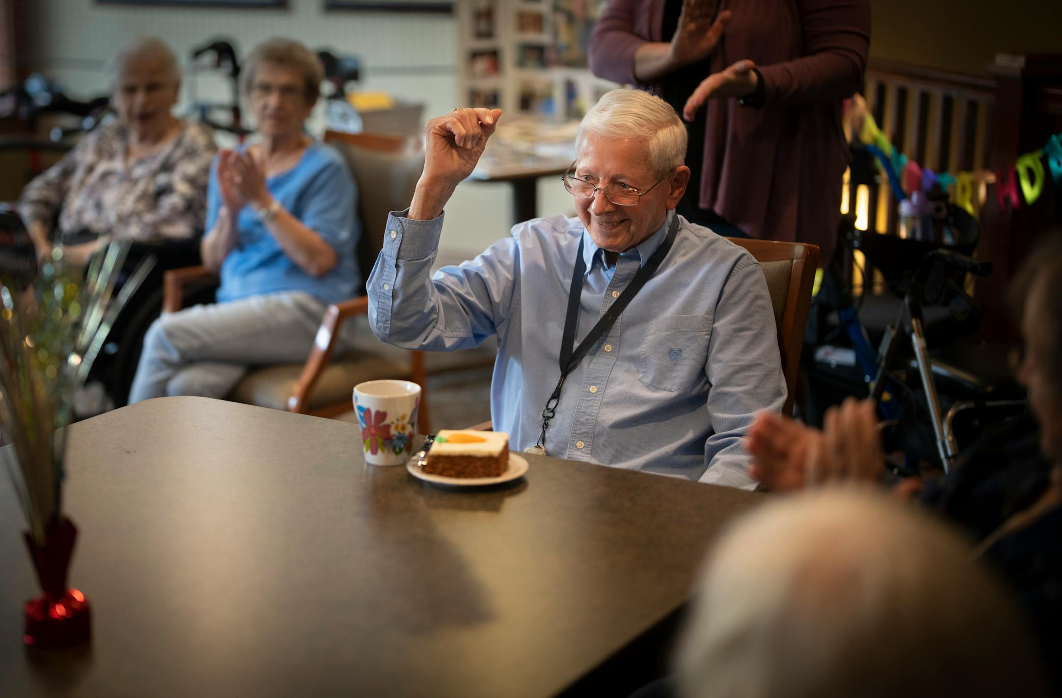 Richard King raises his fist in cheer as he is served a piece of carrot cake while celebrating turning 100 with fellow residents and staff at his home New Perspective Woodbury senior facility in Woodbury, Minn., on Thursday, June 8, 2023. The World War II Air Force Veteran had ten kids and has 45 grandchildren and great-grandchildren who celebrated his birthday at a family party last weekend.