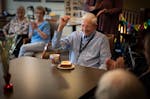 Richard King raises his fist in cheer as he is served a piece of carrot cake while celebrating turning 100 with fellow residents and staff at his home