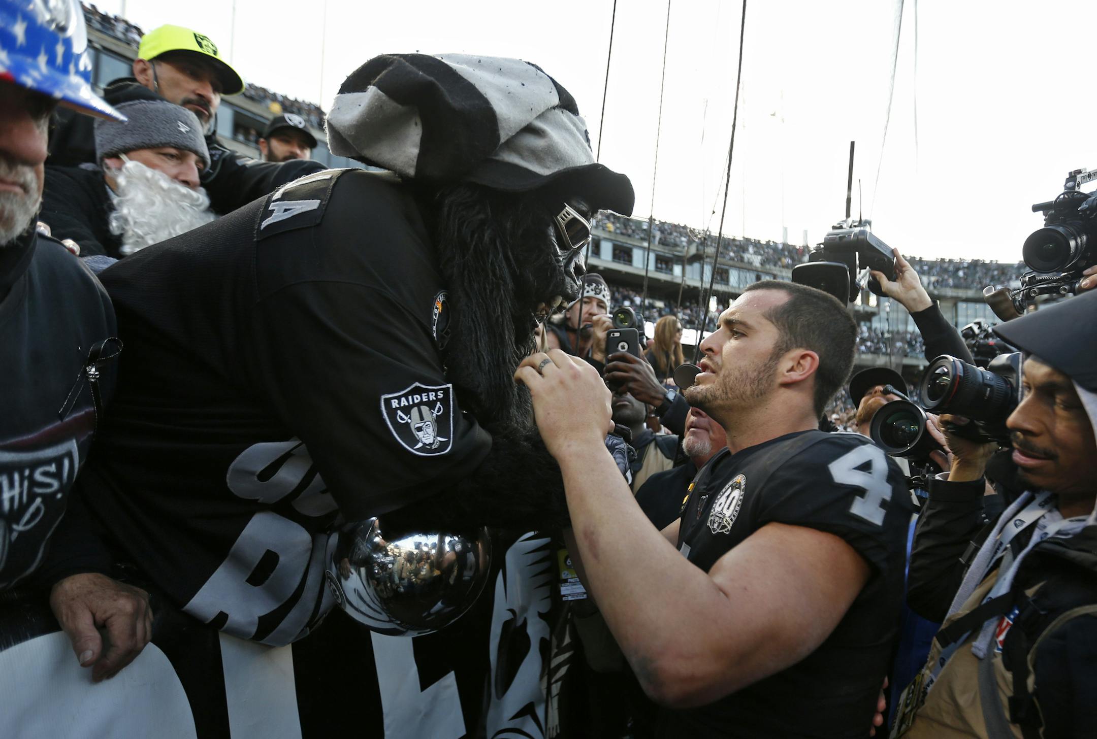 Oakland Raiders quarterback Derek Carr (4) is met by Gorilla Nilla in "The Black Hole" at the end of an NFL football game against the Jacksonville Jaguars in Oakland, Calif., Sunday, Dec. 15, 2019. (AP Photo/D. Ross Cameron)