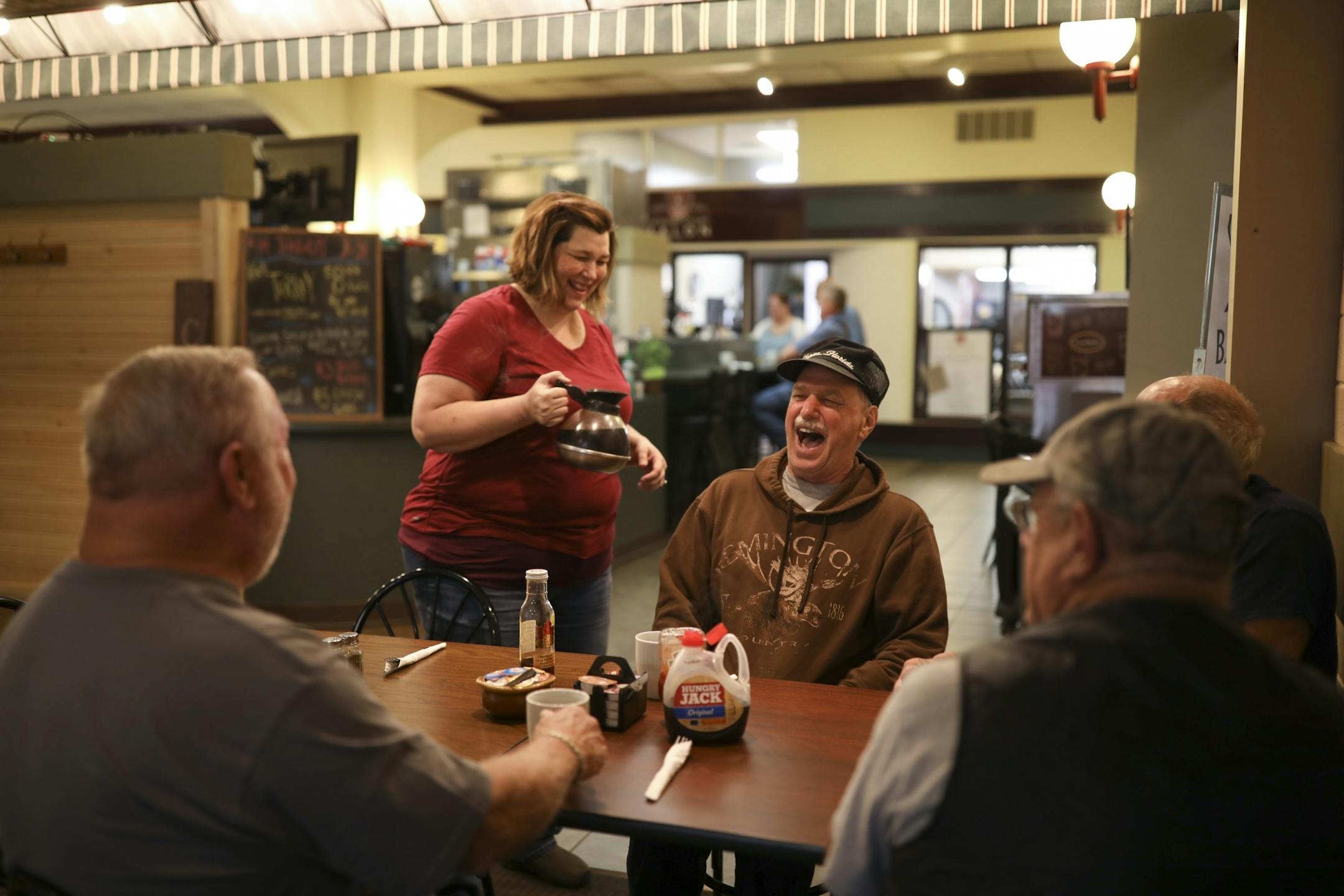 Tracy Bailey served coffee to a group of regulars shortly after her Bailey's Courtyard Cafe opened up for the day Thursday morning. The men, all retired, are, from left, Dick Anderson, Tony Galli, Wayne Nevalainen, and Norman "Butch" Resch, obscured at right.